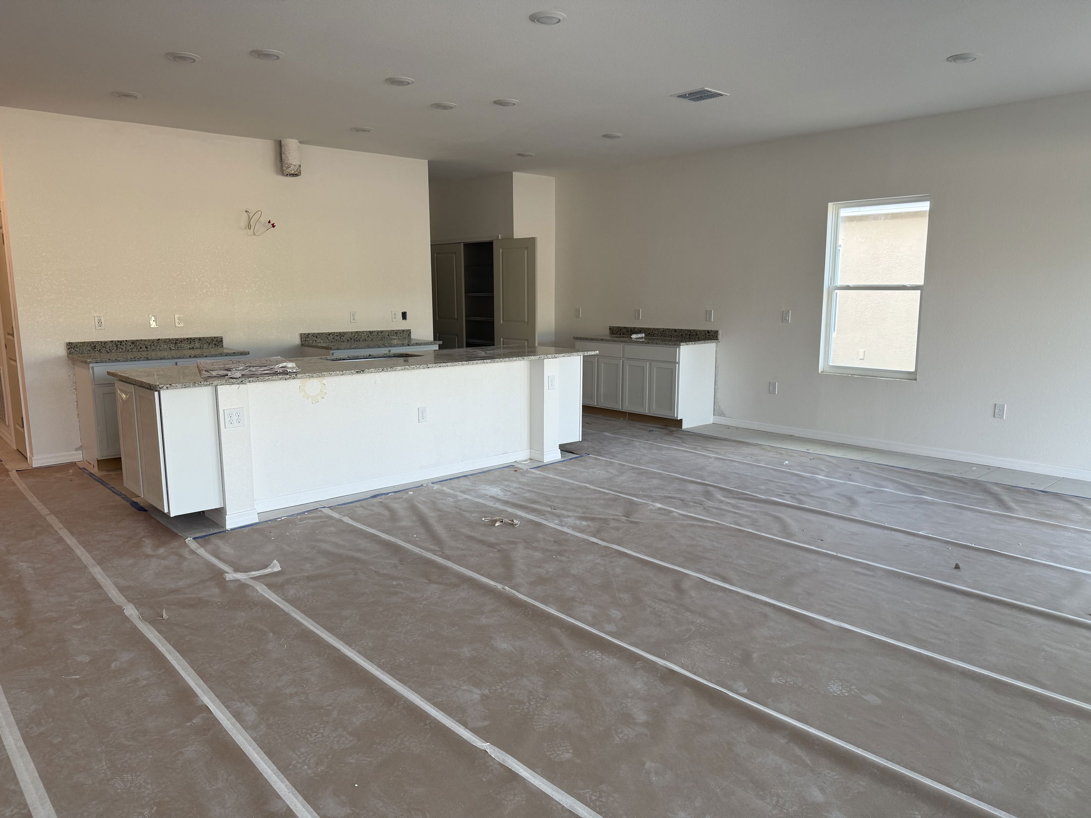 Newly constructed kitchen interior with granite countertops and protective floor covering.