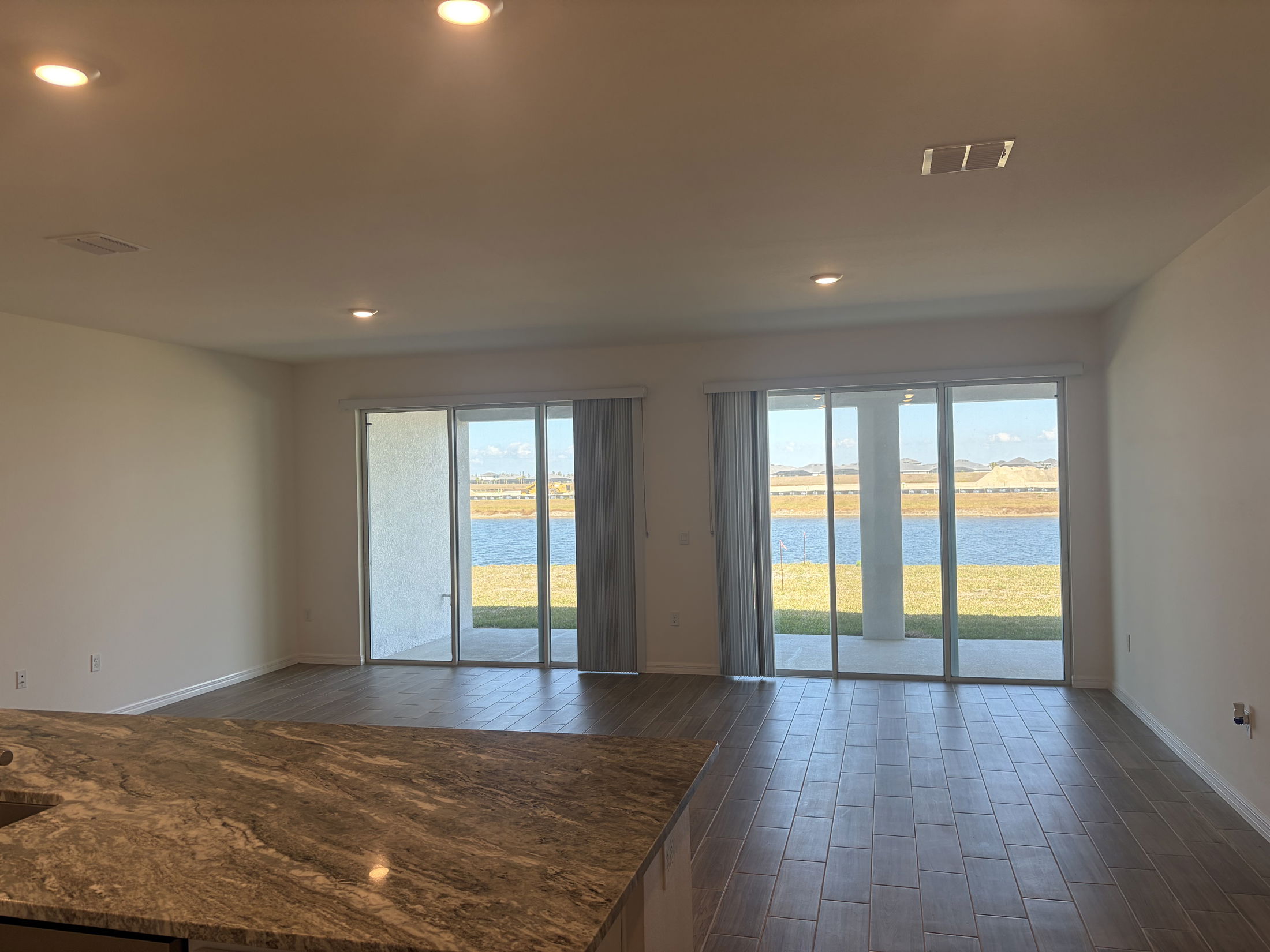 Spacious modern living room with sliding glass doors overlooking a serene lake and mountain view.