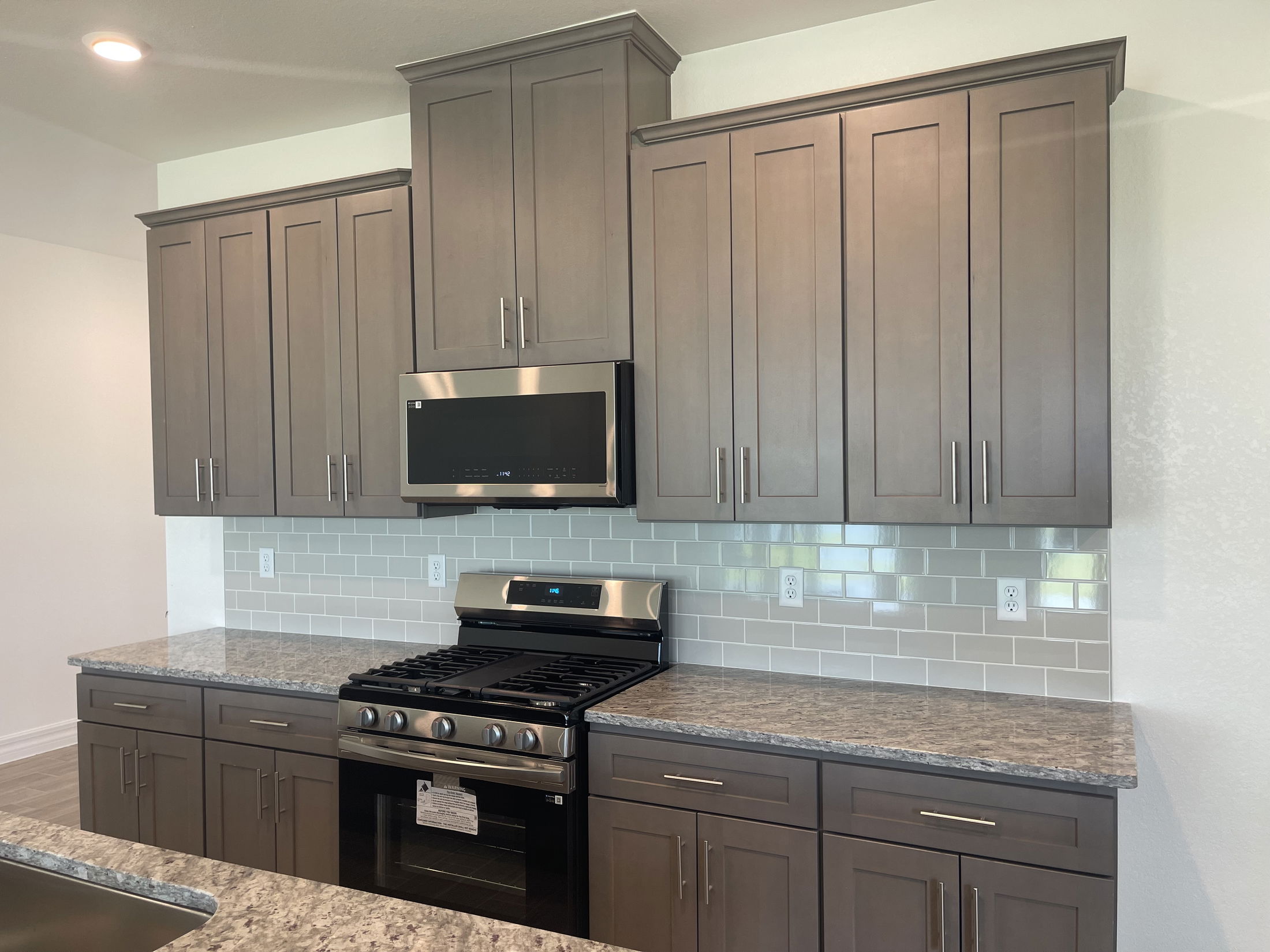 Modern kitchen with gray cabinets, stainless steel appliances, and a sleek subway tile backsplash.