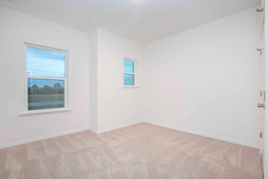 Bright and spacious empty room with white walls and large windows.