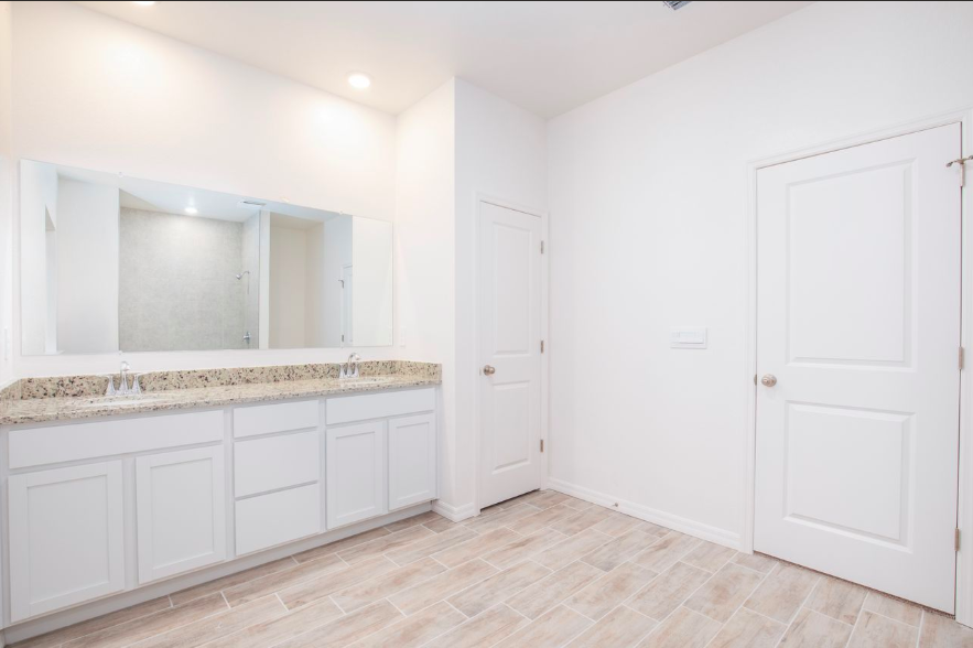 Modern bathroom interior featuring a double-sink vanity with a granite countertop, large mirror, and tiled flooring.