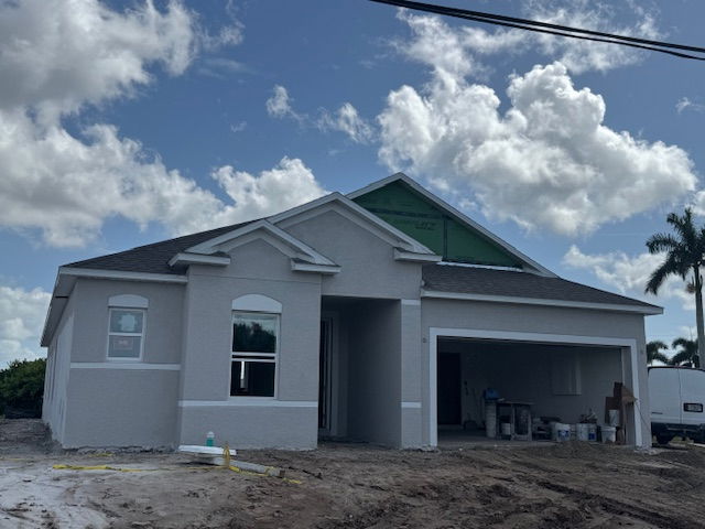 Newly constructed single-story house with garage under a partly cloudy sky.