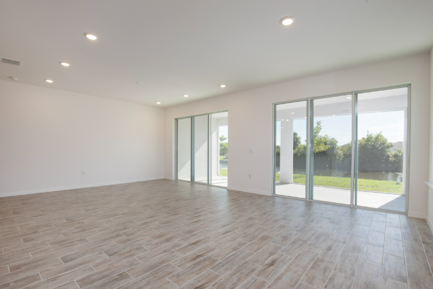 Spacious modern living room with large windows, natural light, and wooden tile flooring.