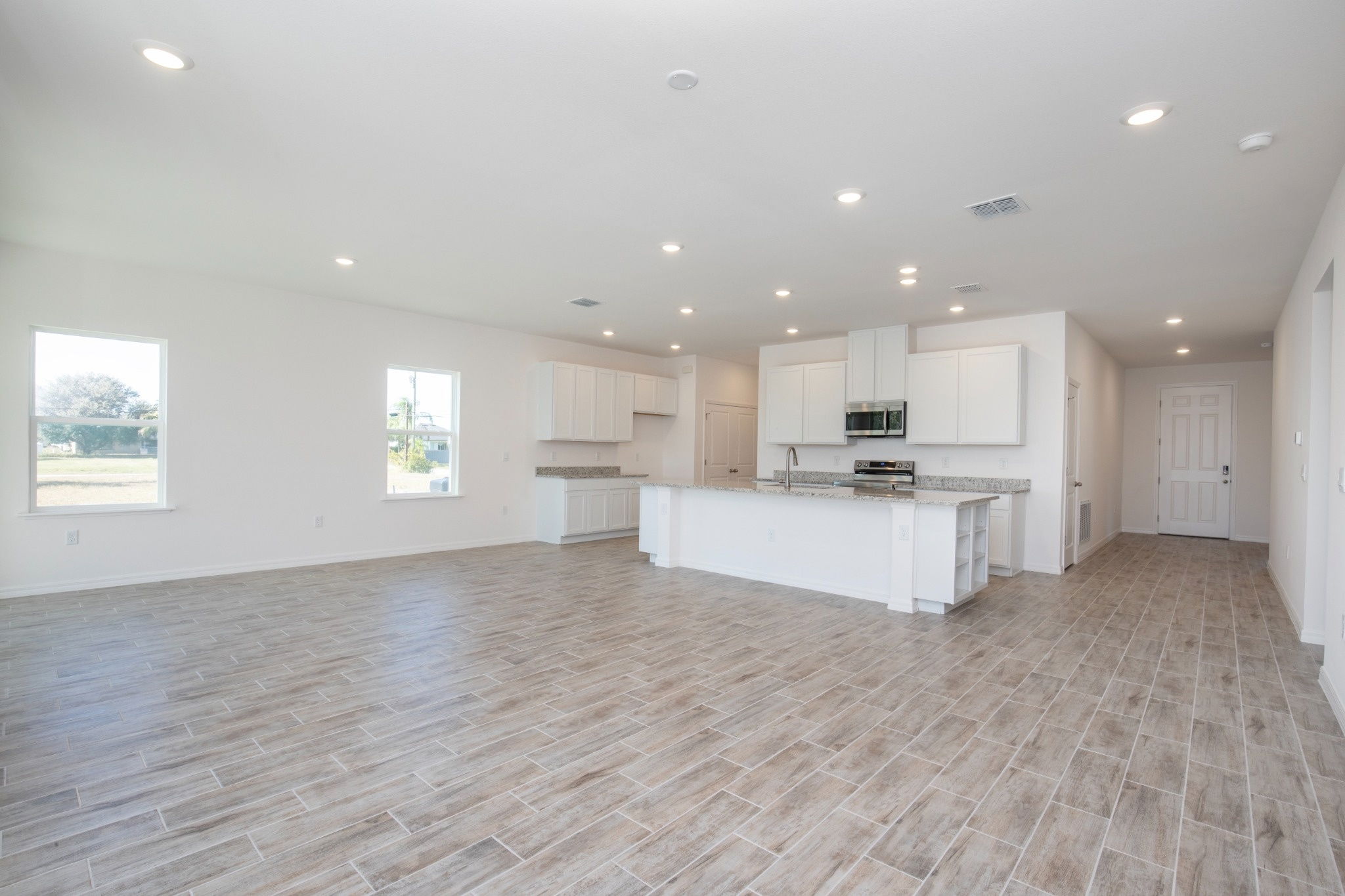 Spacious modern kitchen and living area with granite countertops, tile flooring, and ample natural light.