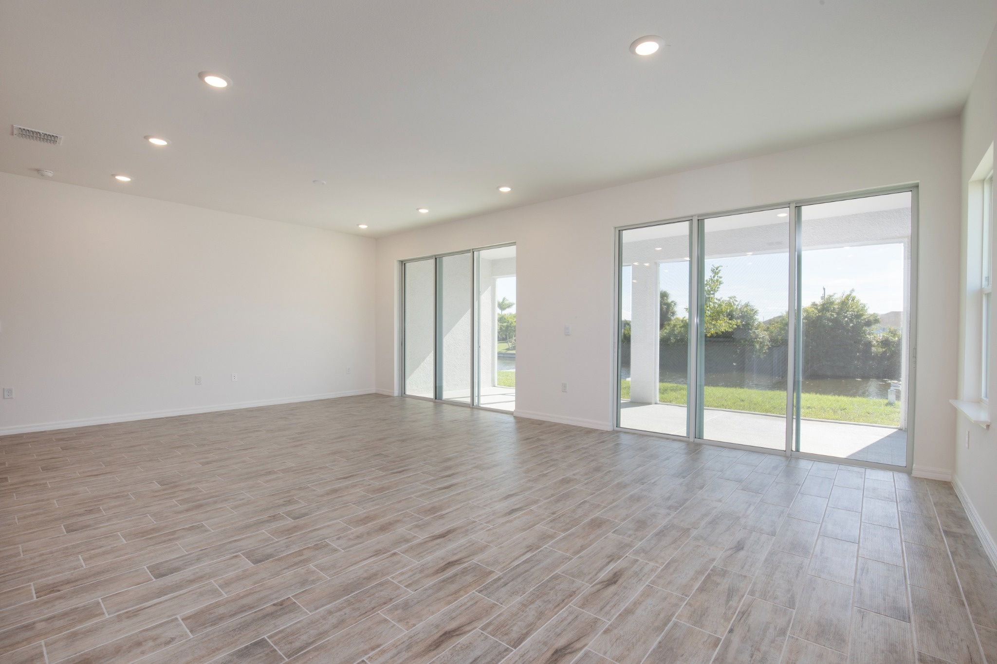 Bright and spacious living room featuring large windows and modern tile flooring.