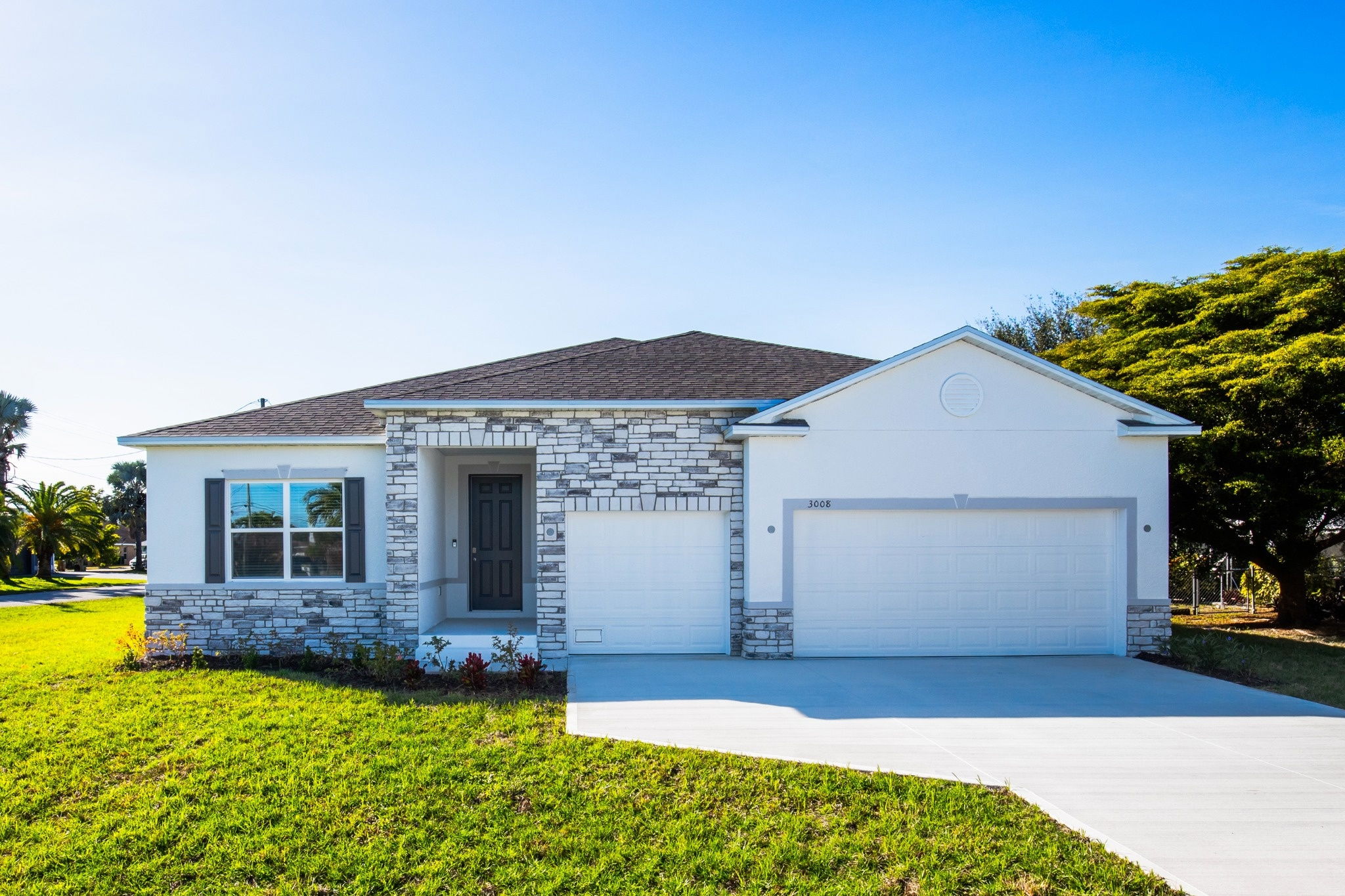 Modern single-family home with stone accents and a two-car garage on a sunny day.