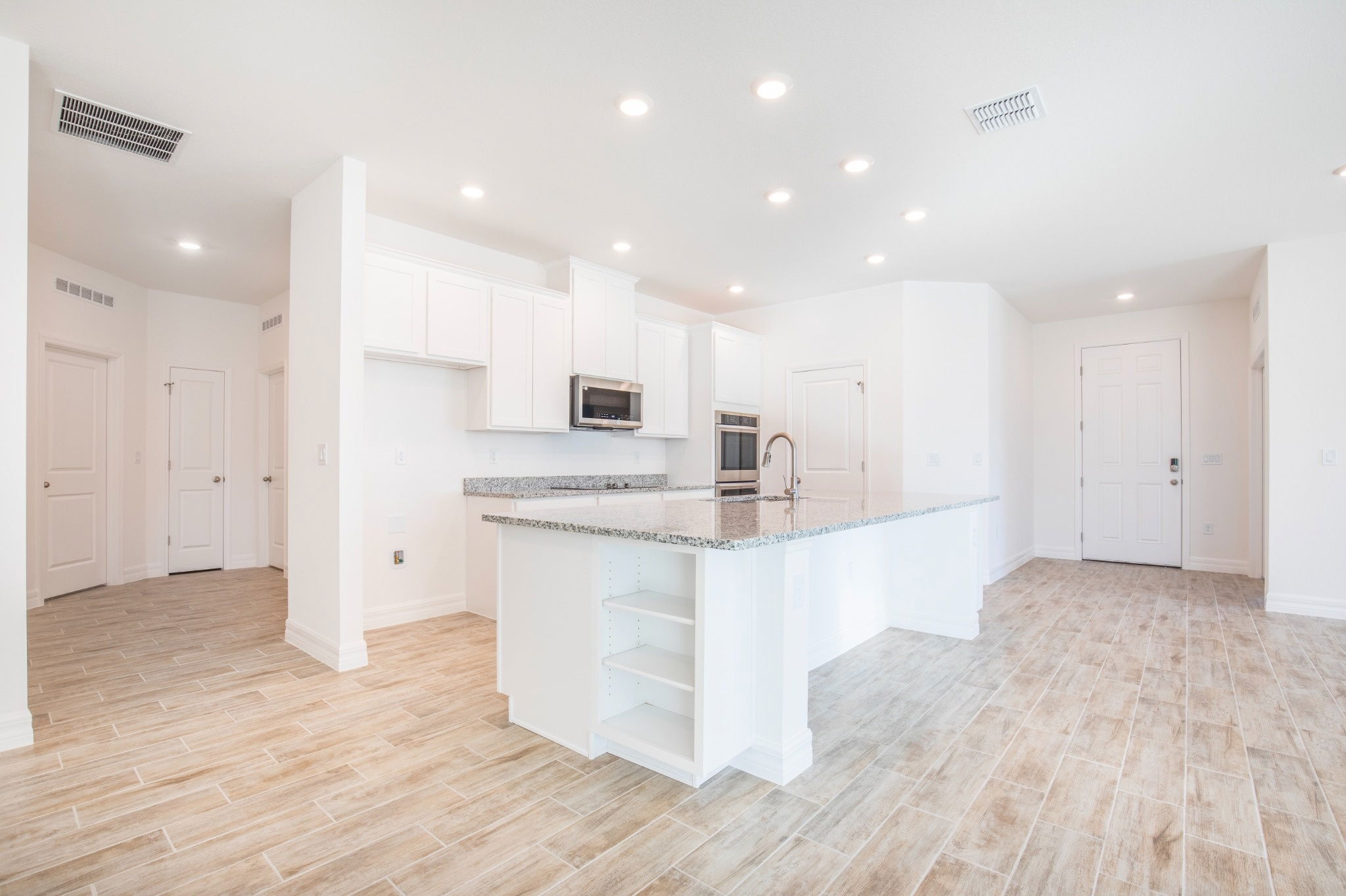 Bright and modern kitchen featuring white cabinetry, granite countertops, and stylish lighting in an open-concept layout.