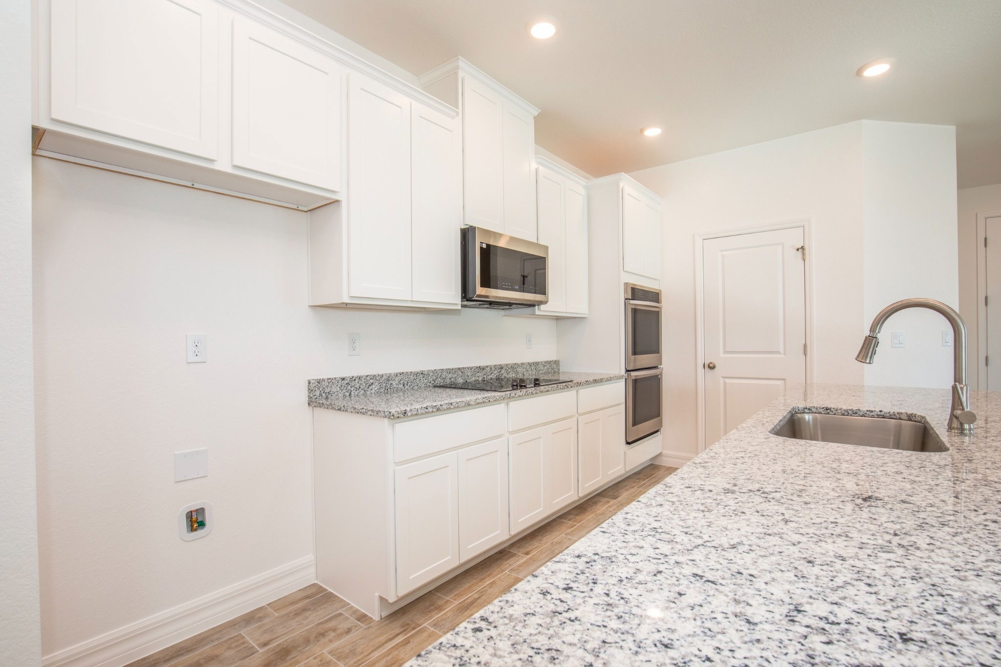 Modern kitchen featuring white cabinets, stainless steel appliances, and a granite countertop.