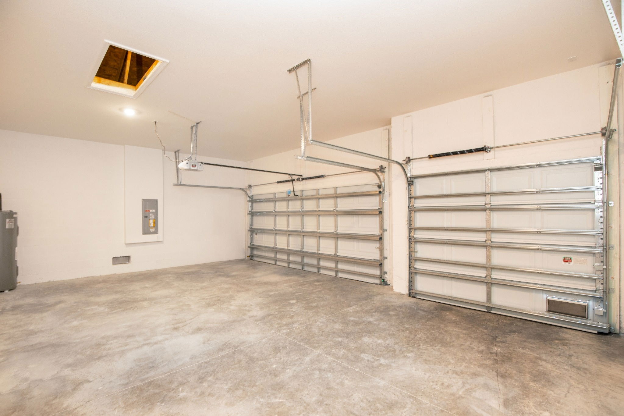 Spacious and clean garage interior with two garage doors and ceiling with access hatch.