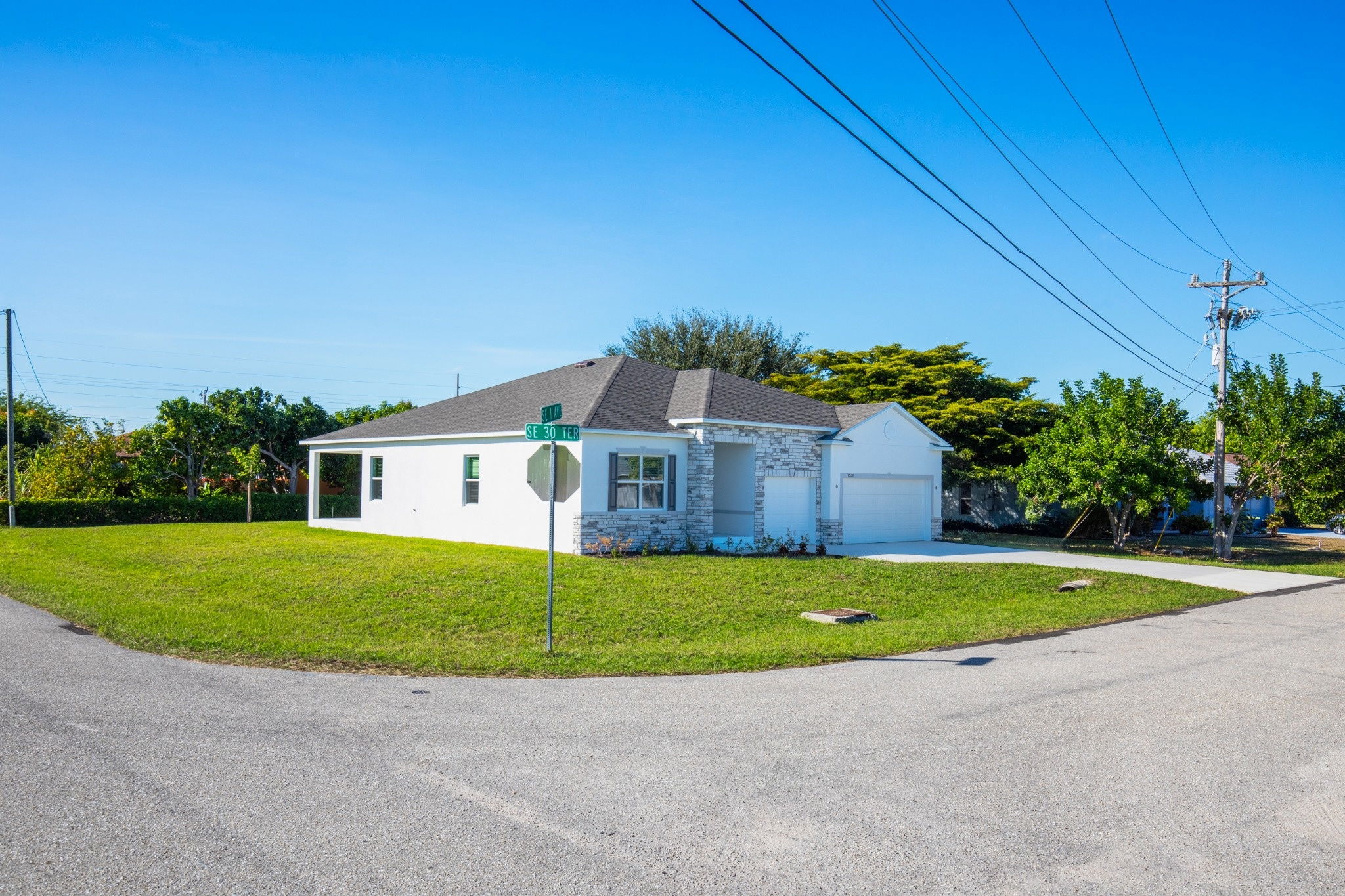 A beautiful single-family home with a gray roof and stone accents located at the corner of SE 30th Terrace in a lush, green neighborhood.