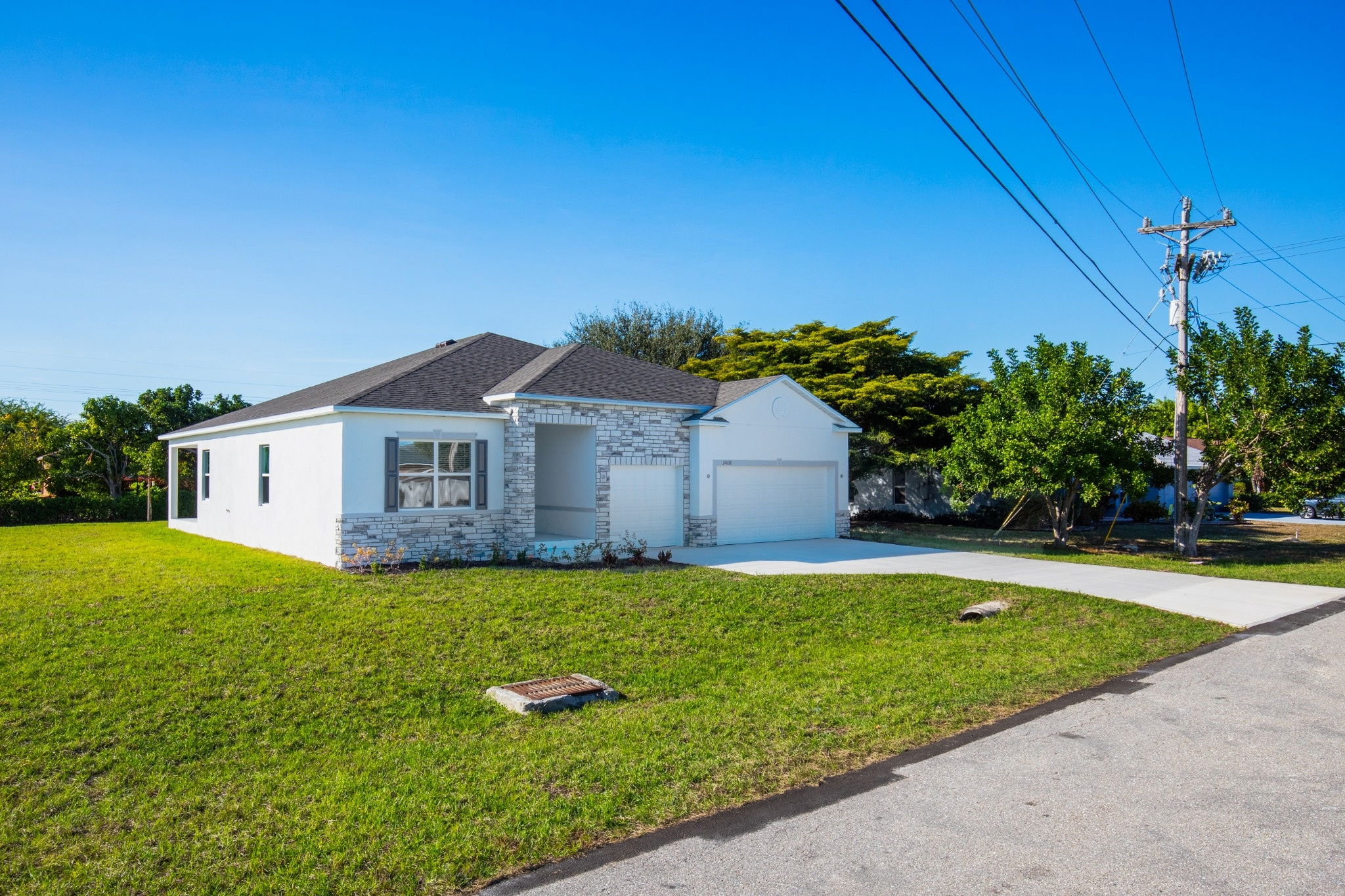 Modern single-family home with a stone facade, spacious lawn, and two-car garage in a suburban neighborhood.