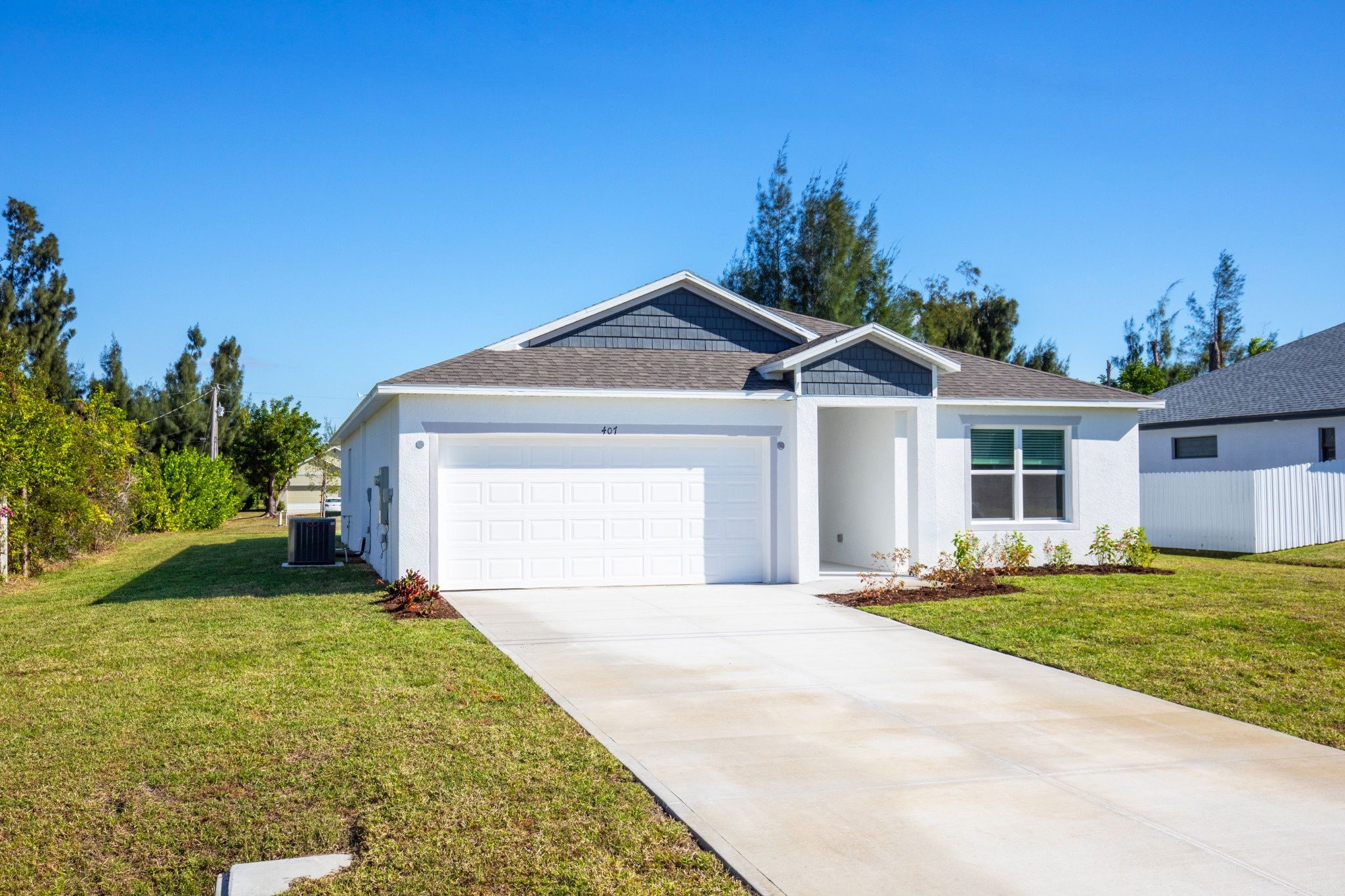 Modern single-story house with a landscaped yard and a driveway on a sunny day.