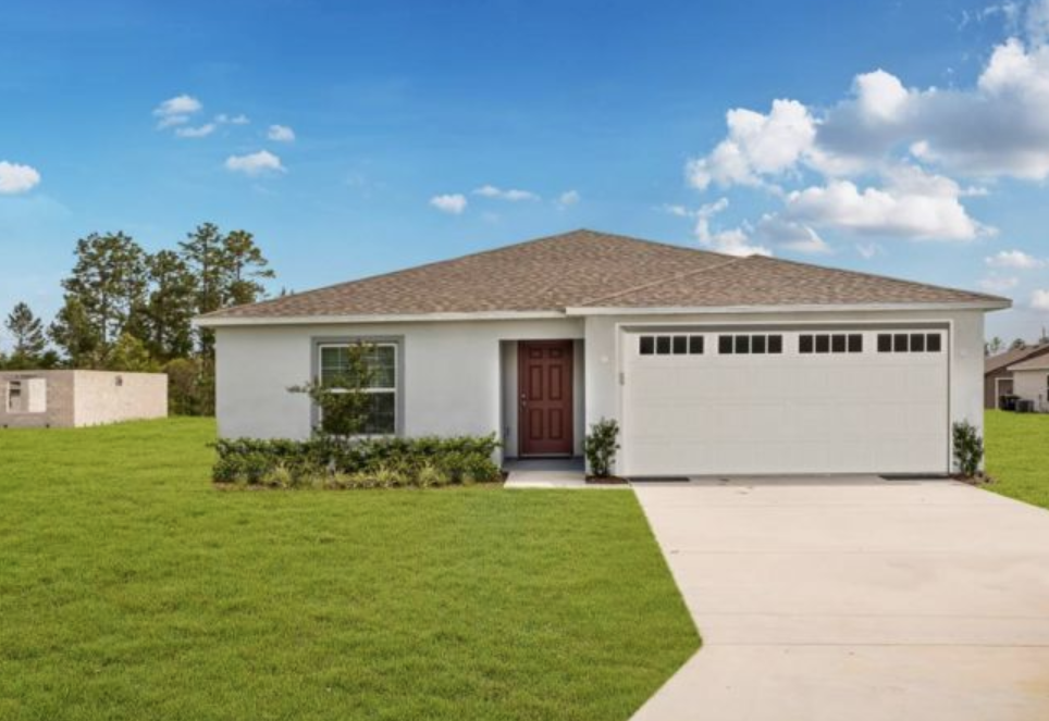 Single-story suburban home with attached garage on a spacious green lawn under a clear blue sky.