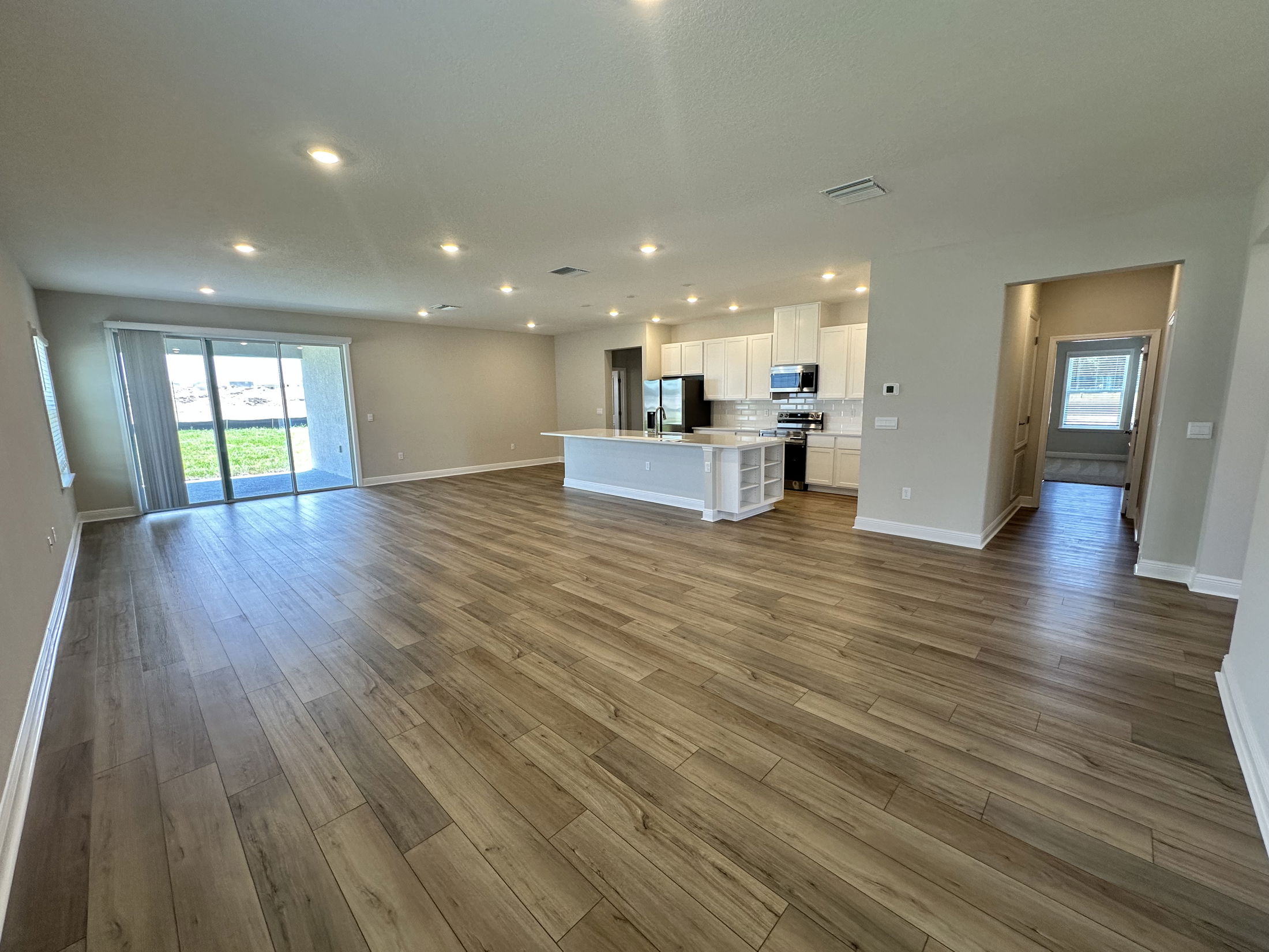 Spacious modern open-concept kitchen and living area with hardwood floors and large windows.