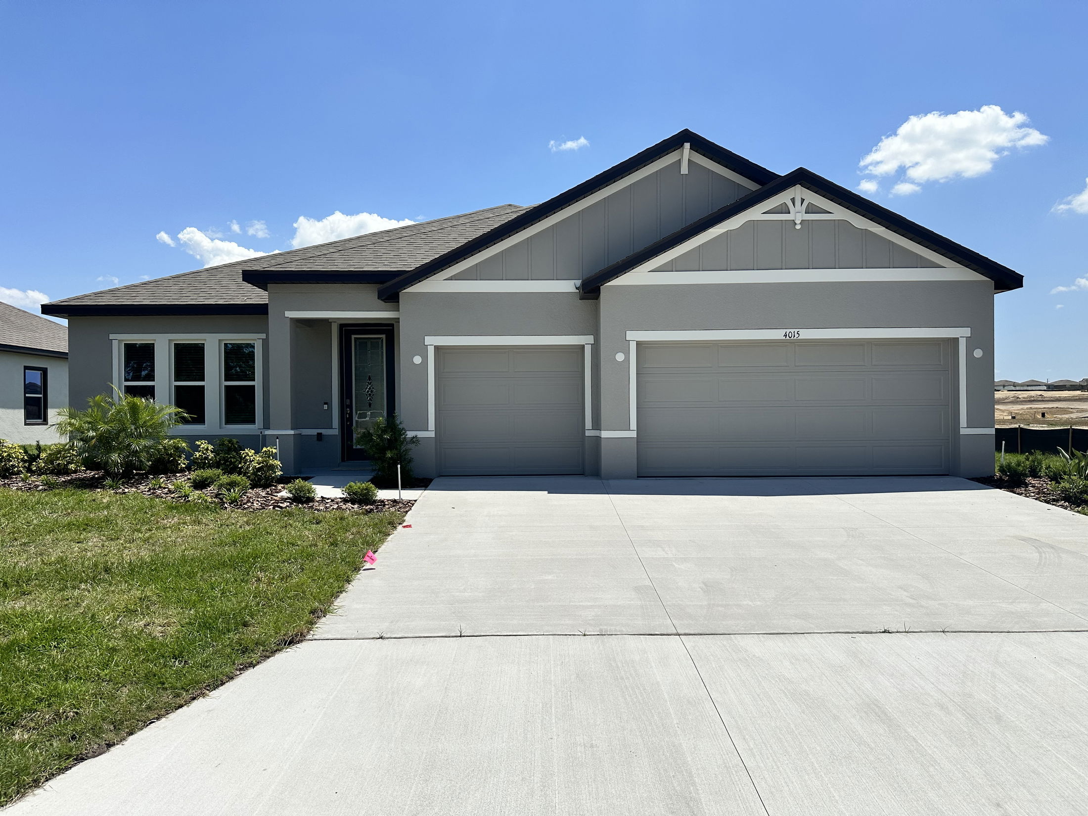 Modern gray single-story home with a spacious driveway and two-car garage under a clear blue sky.