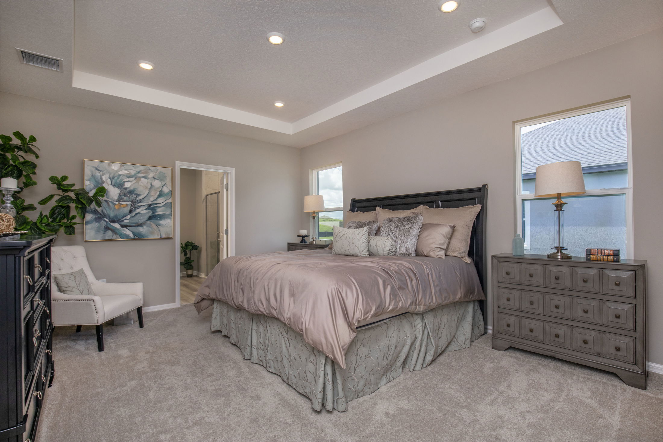 Modern bedroom with elegant decor, a plush bed, decorative pillows, plants, and soft lighting.