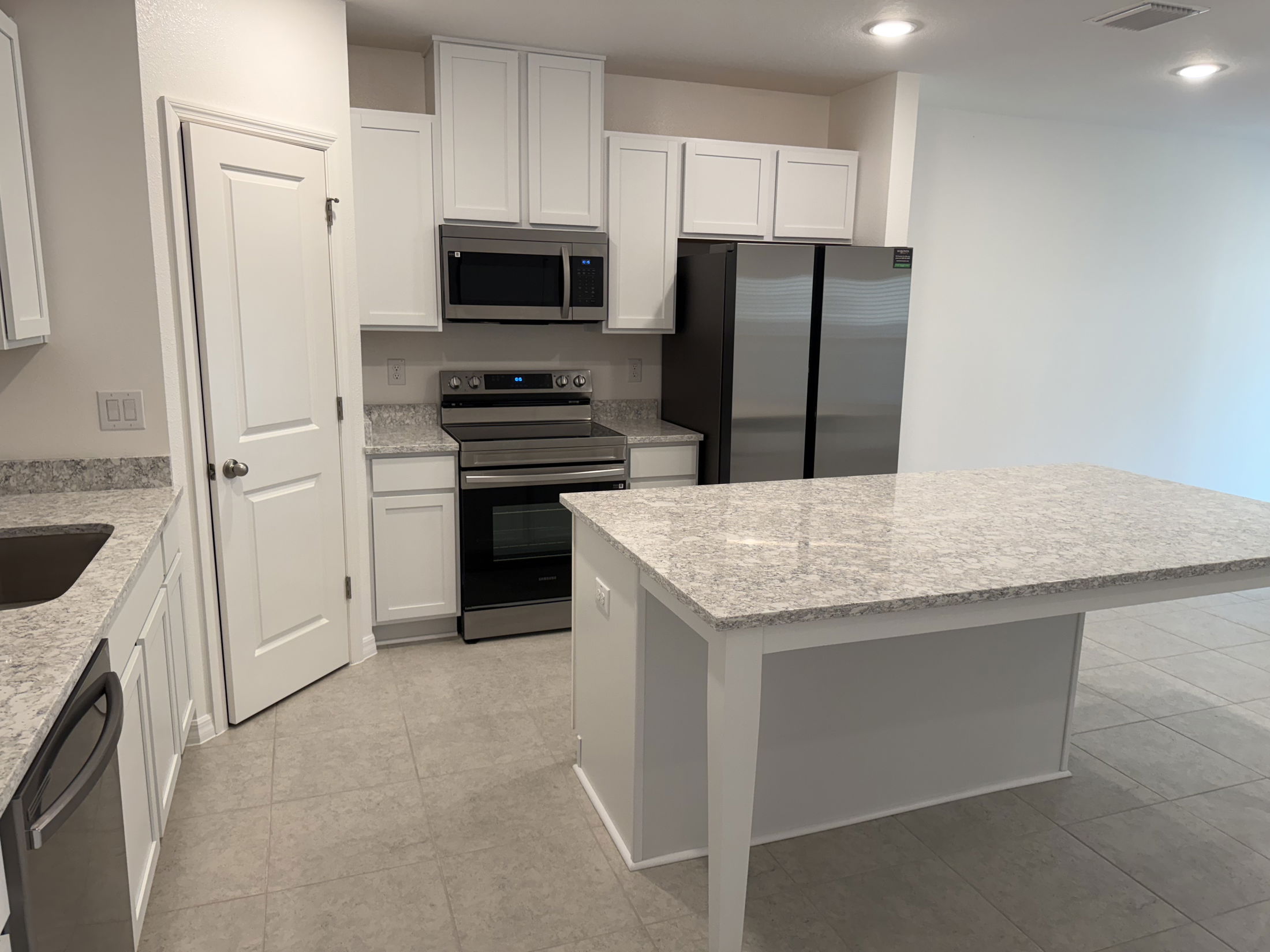 Modern kitchen with white cabinets, granite countertops, stainless steel appliances, and a large island.