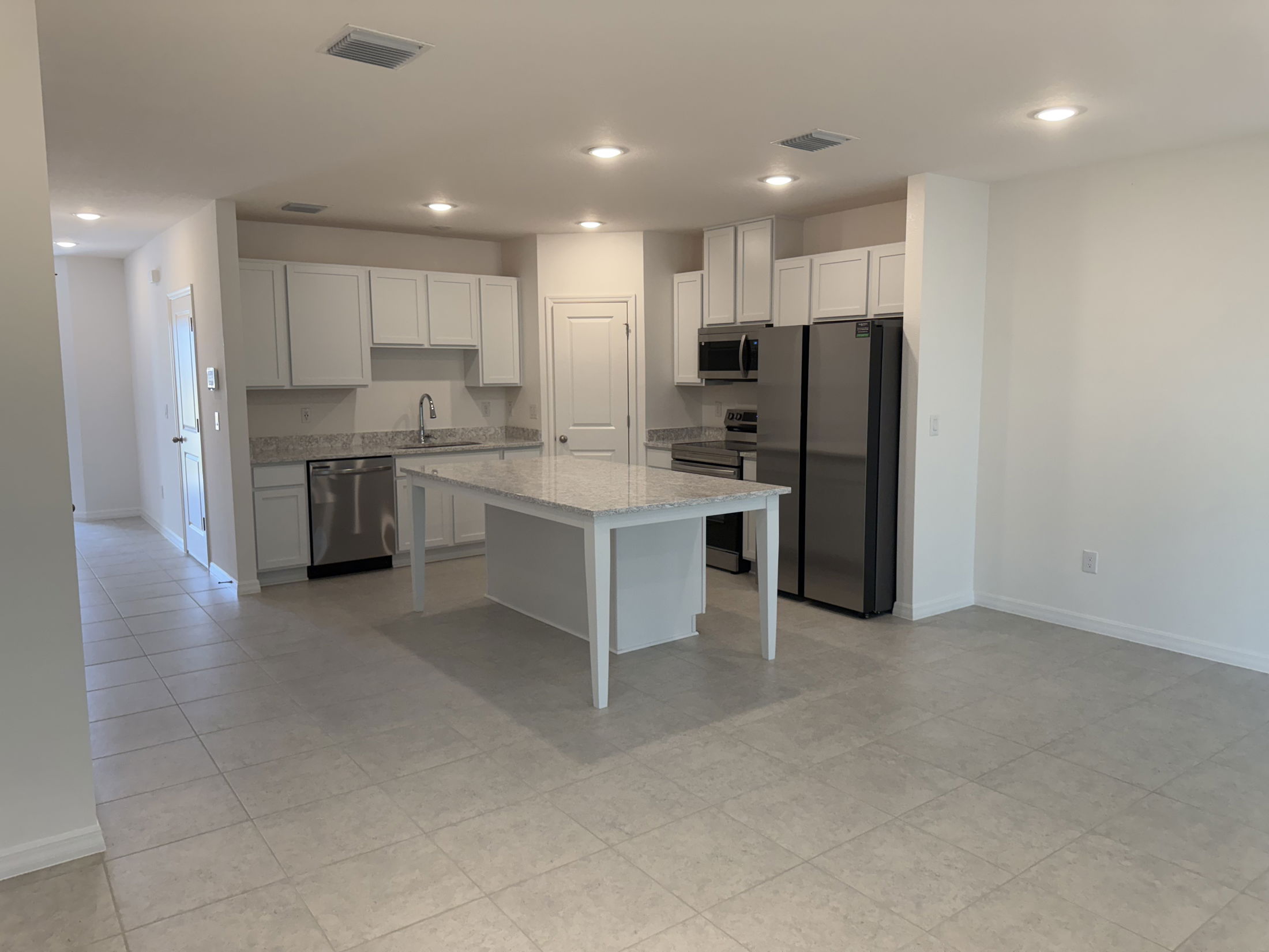 Modern kitchen with white cabinets, granite countertops, stainless steel appliances, and a large center island.