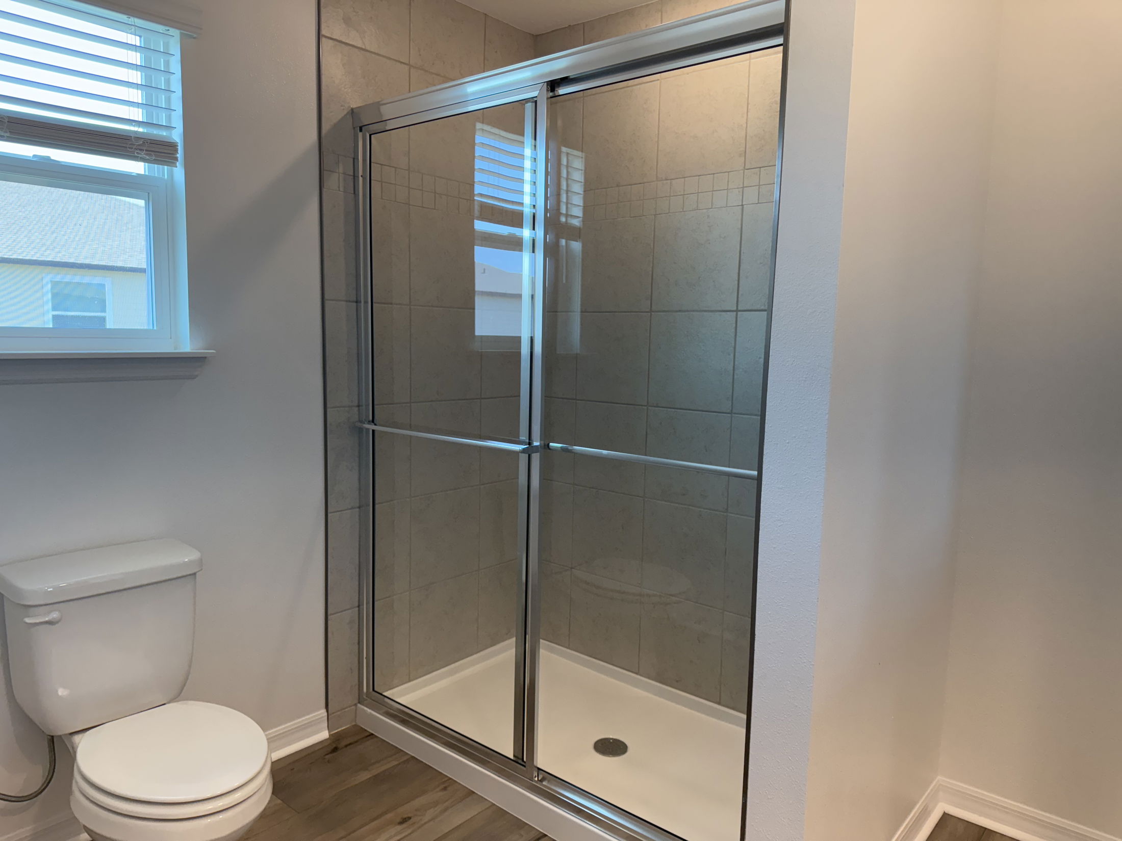 Modern bathroom featuring a glass-enclosed shower with sliding doors and adjacent toilet.