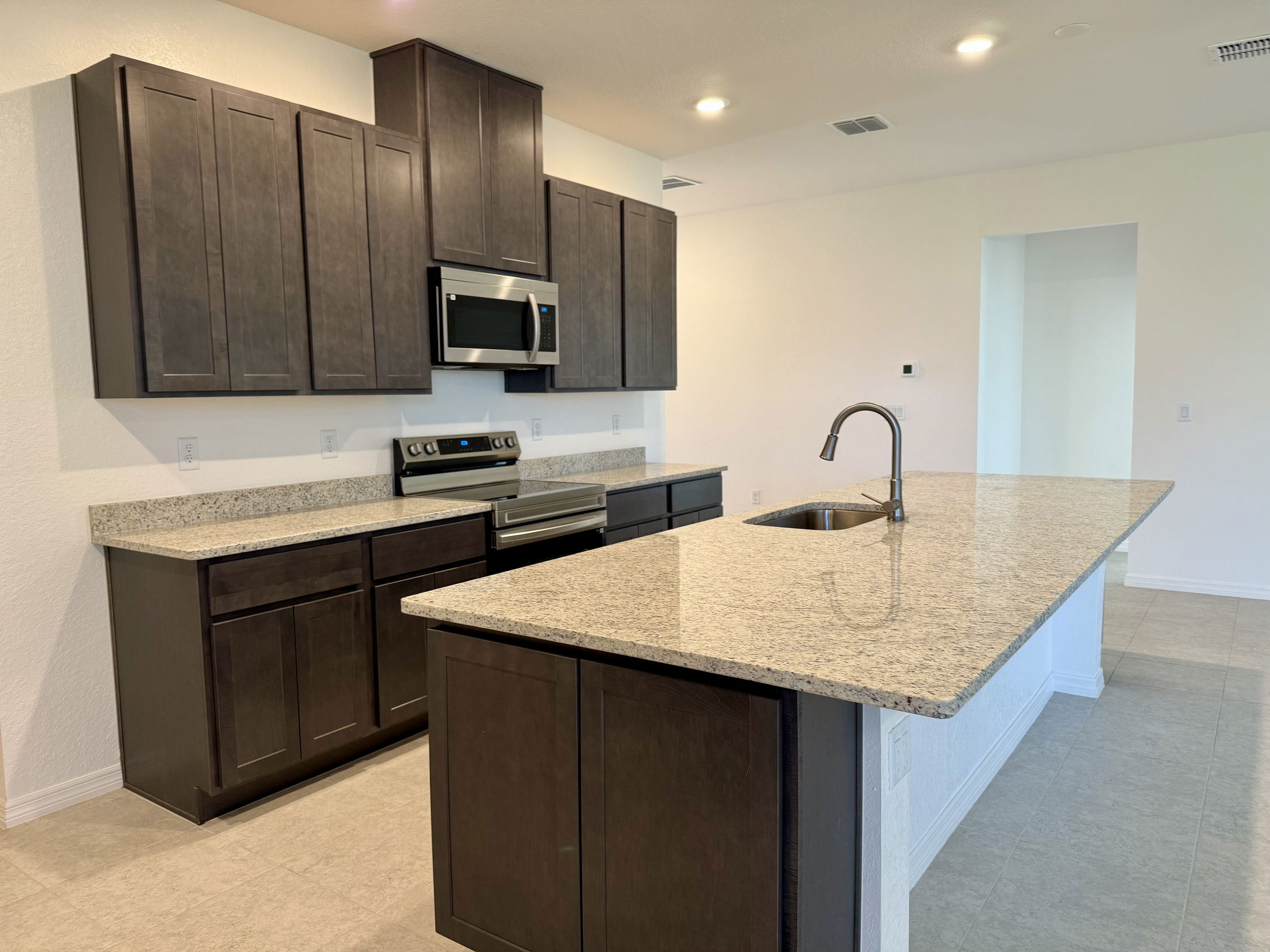 Modern kitchen with granite countertops, dark wood cabinets, and stainless steel appliances.