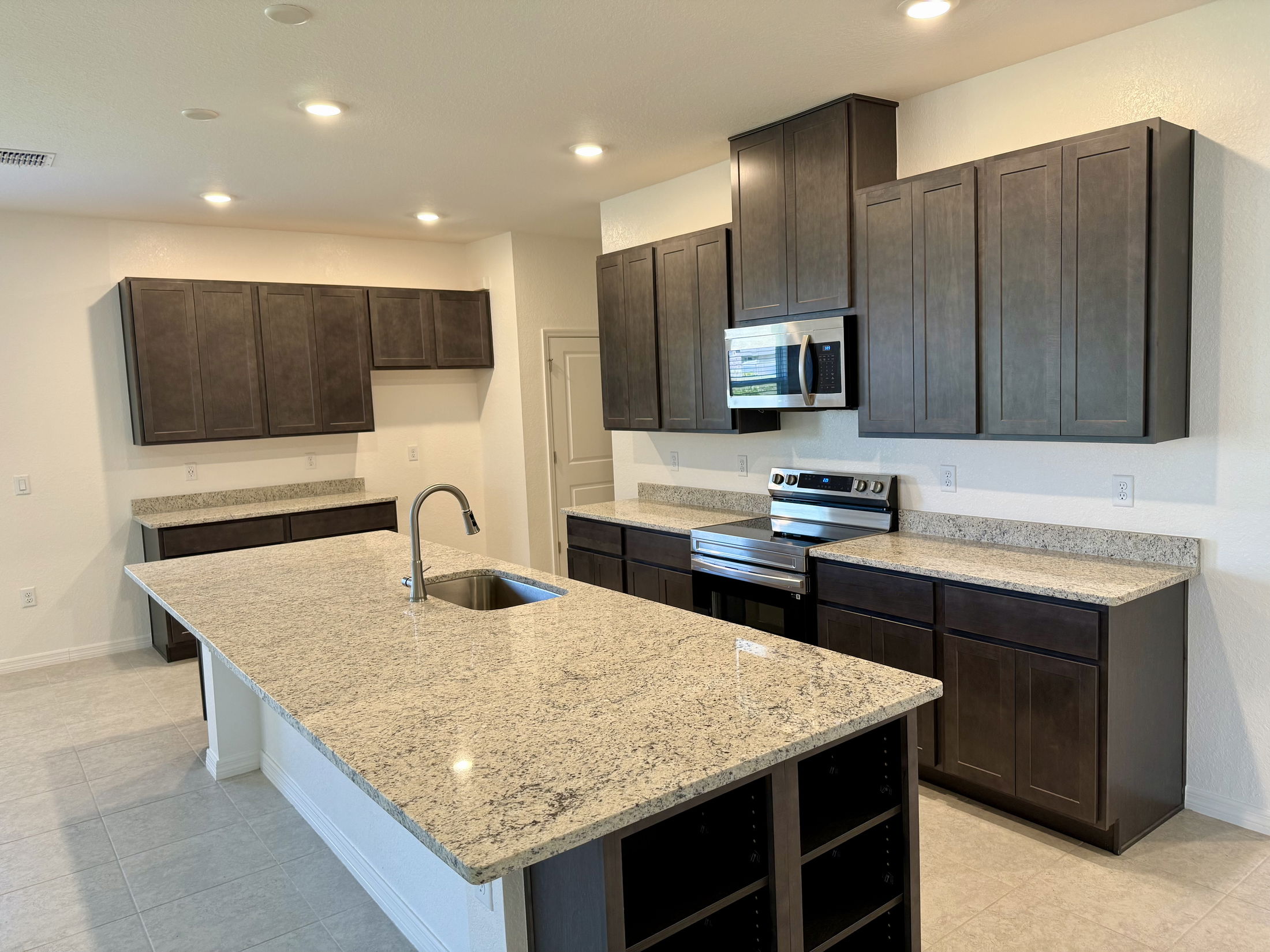 Modern kitchen with dark wood cabinets, granite countertops, and stainless steel appliances.
