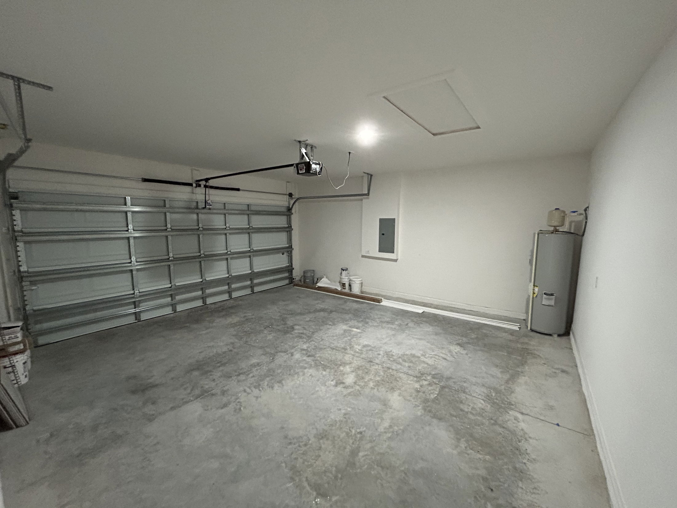 Empty garage interior featuring a concrete floor, metal garage door, and wall-mounted storage.