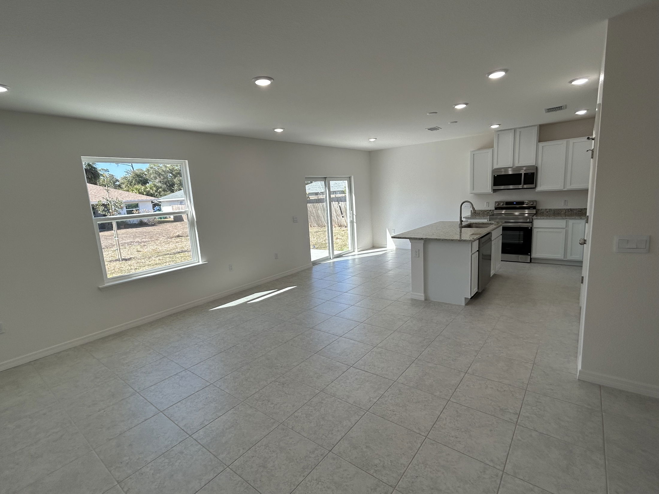Modern open-concept kitchen and living area with ceramic tile flooring and ample natural light.