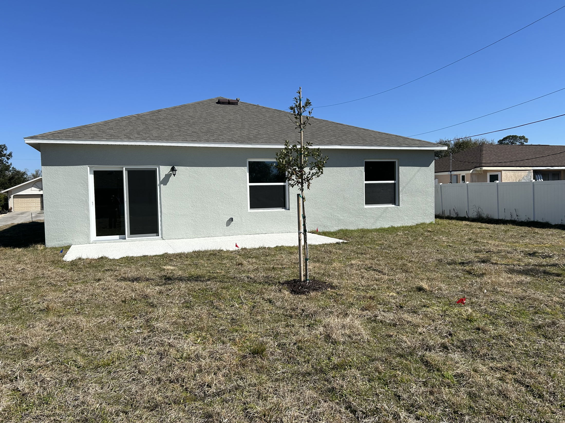 Back view of a modern single-family home with a newly landscaped yard and clear blue sky.