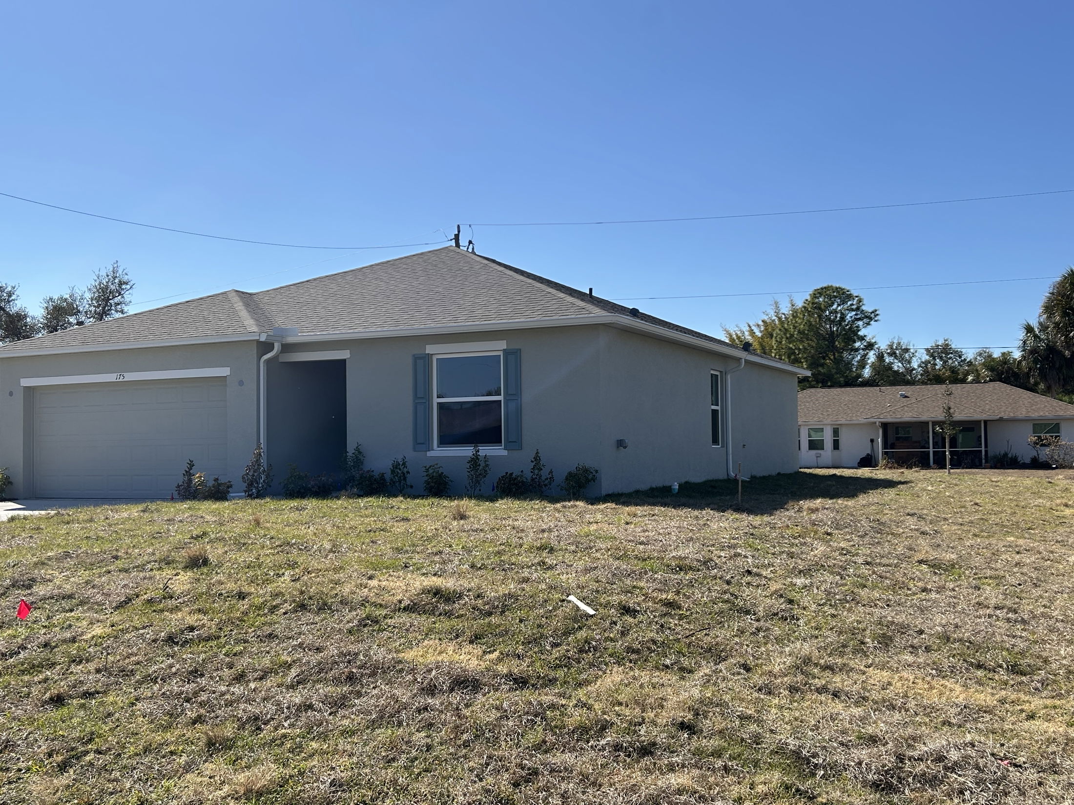Exterior view of a modern single-family home with a garage and green lawn under a clear blue sky.