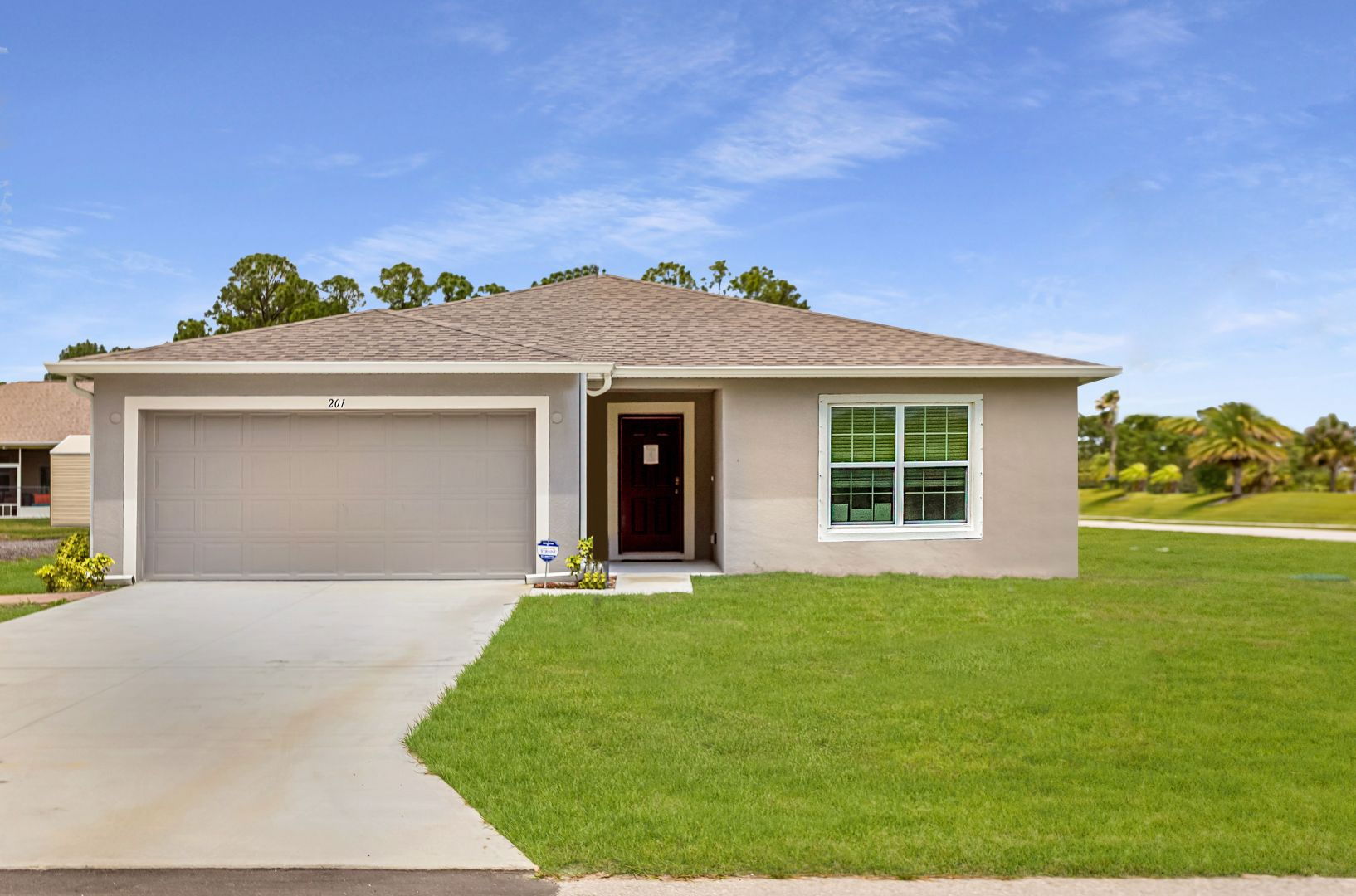 A modern, single-story home with a two-car garage and manicured lawn under a clear blue sky.