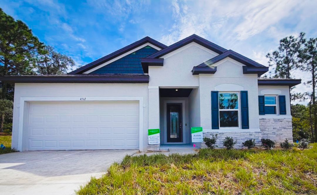 A modern single-family home with a light exterior, dark roof, and a two-car garage, set in a grassy area.