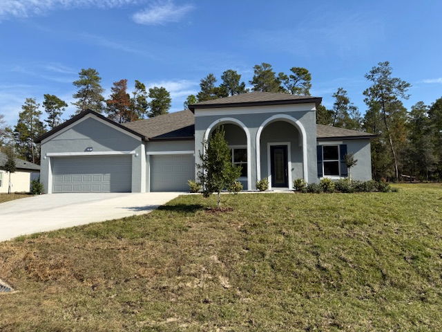 Modern single-family home with a three-car garage and arched entryway, surrounded by a grassy lawn and trees.