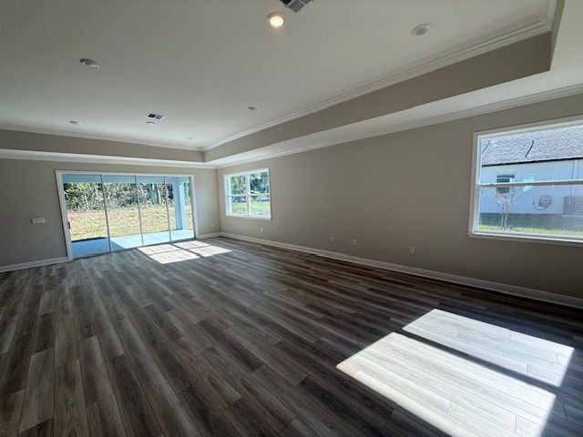 Spacious empty living room with wood flooring, large windows, and sliding glass doors leading to a backyard.