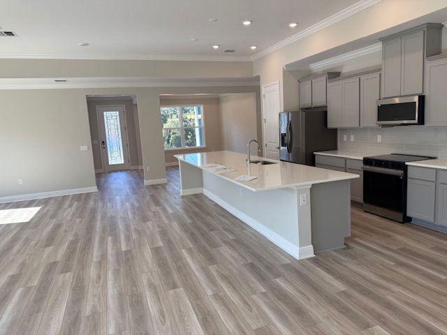 Modern open-concept kitchen and living area with light wood flooring, gray cabinets, and a central island.