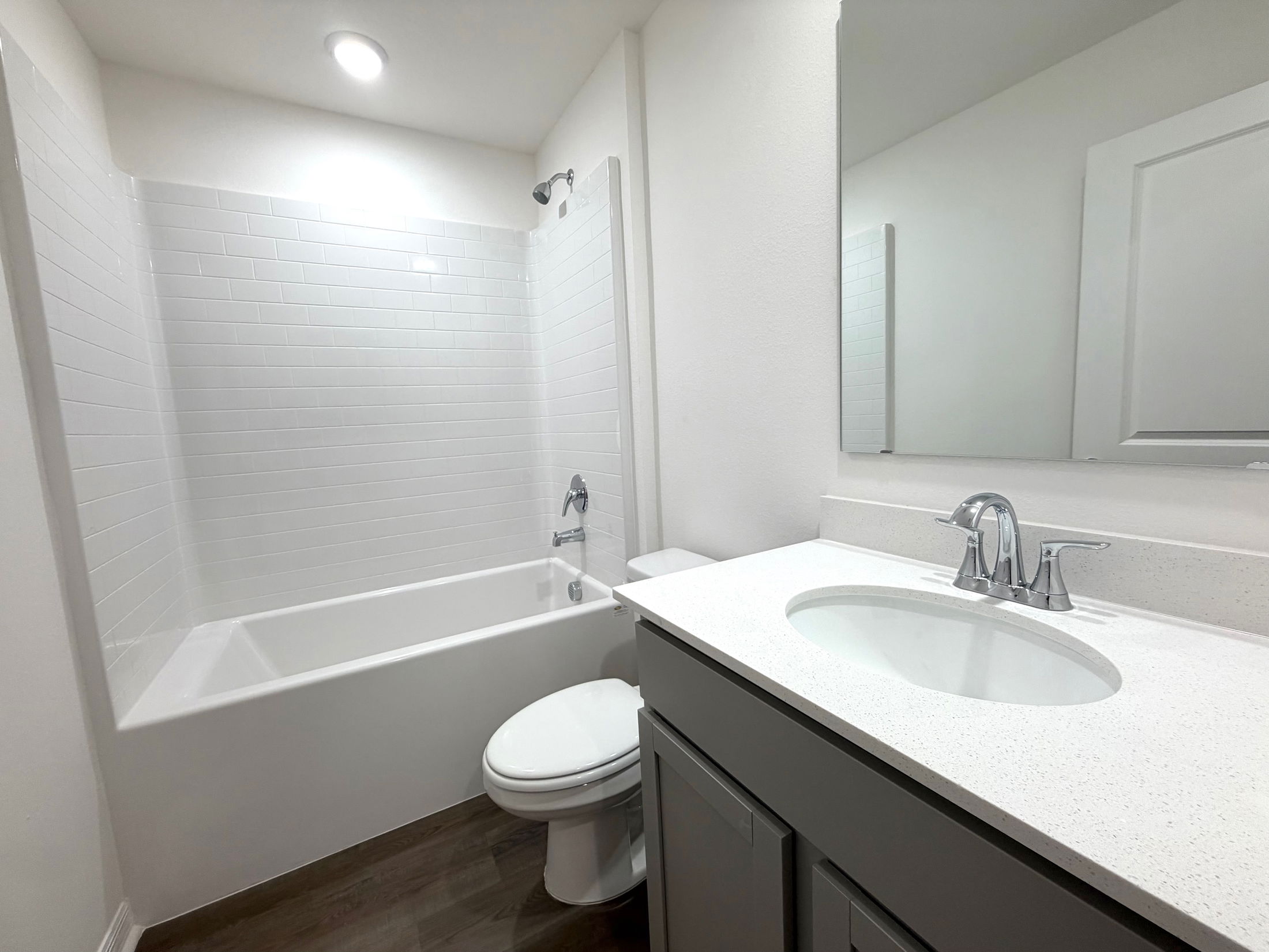 Modern white bathroom featuring a sleek vanity, bathtub with white tile surround, and polished chrome fixtures.