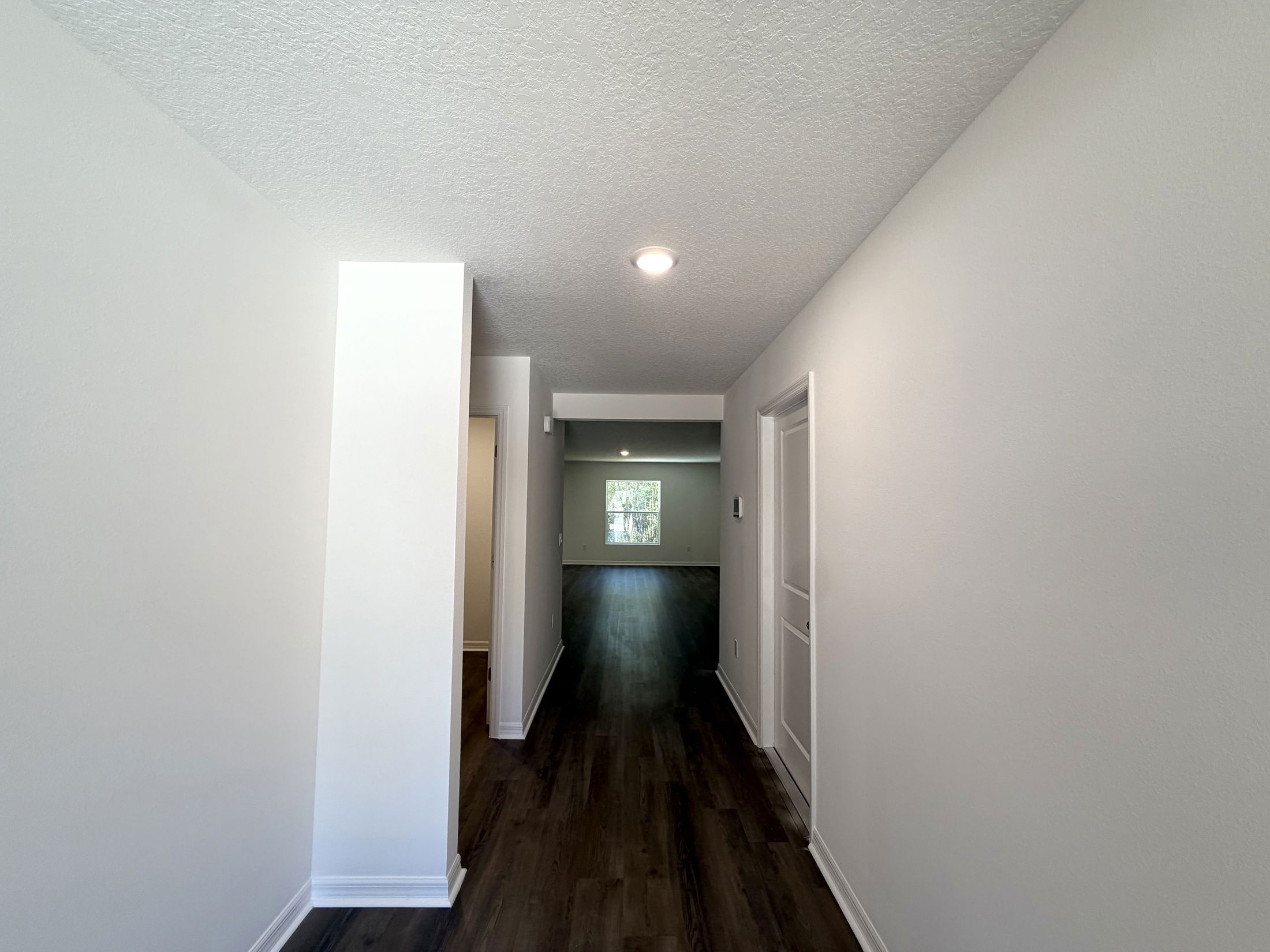 Spacious and bright hallway leading to a living area with natural light and modern flooring.
