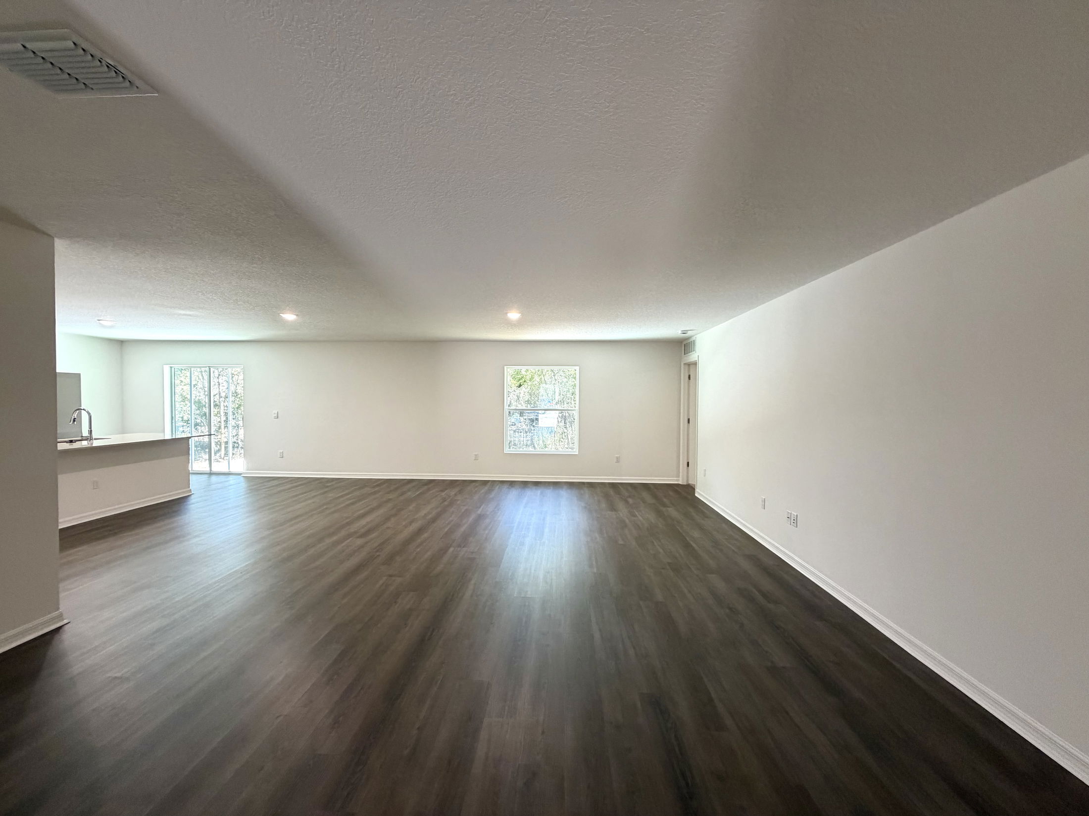 Spacious, modern living room with hardwood flooring and natural light coming from large windows.