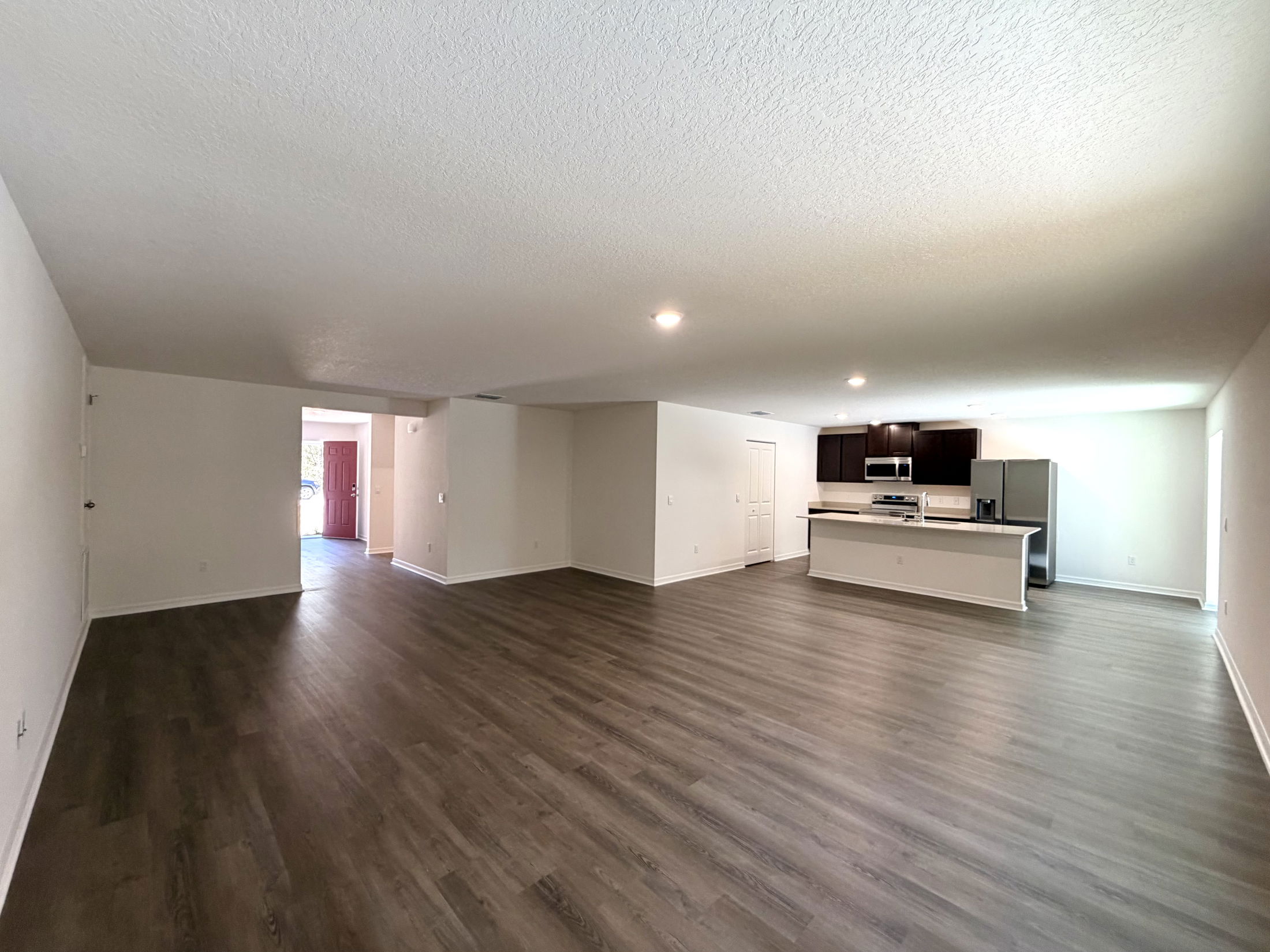 Spacious open living area with modern kitchen featuring dark cabinetry and stainless steel appliances.