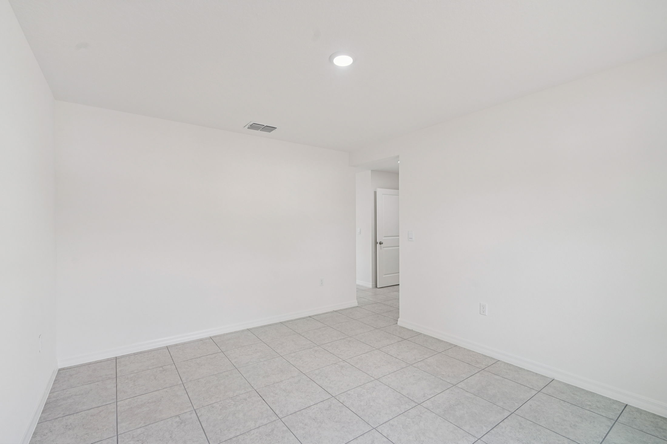 Bright and spacious living area with white walls and tile flooring, ideal for modern home decor.