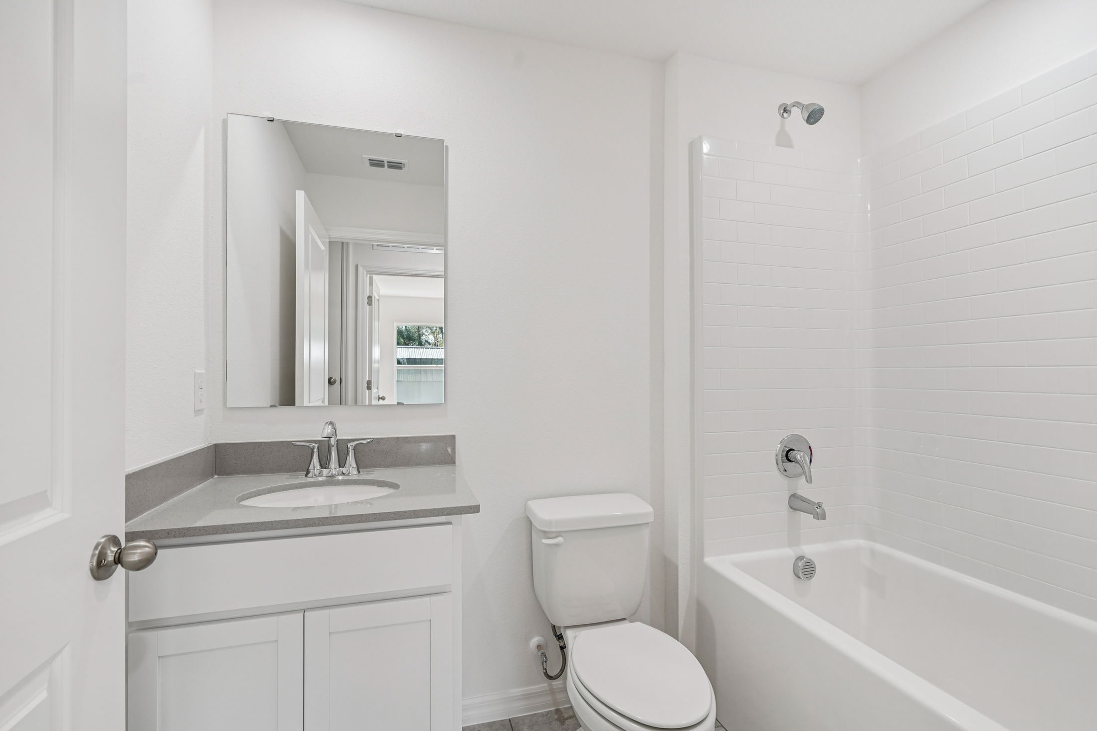 Modern bathroom with a white tiled shower, sleek bathtub, and contemporary fixtures.