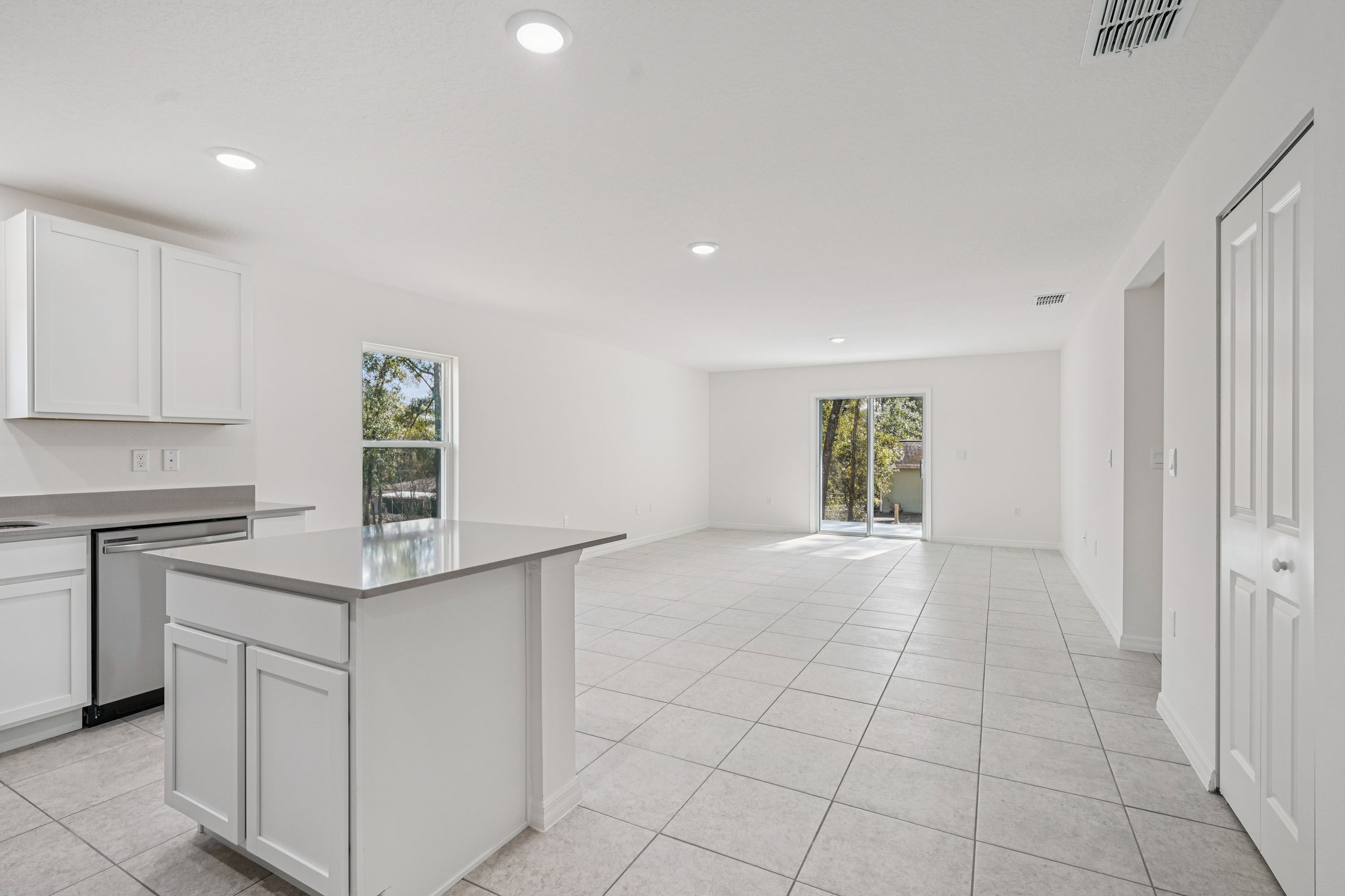 Modern open-concept kitchen and living area with white cabinets, sleek countertops, and ample natural light.