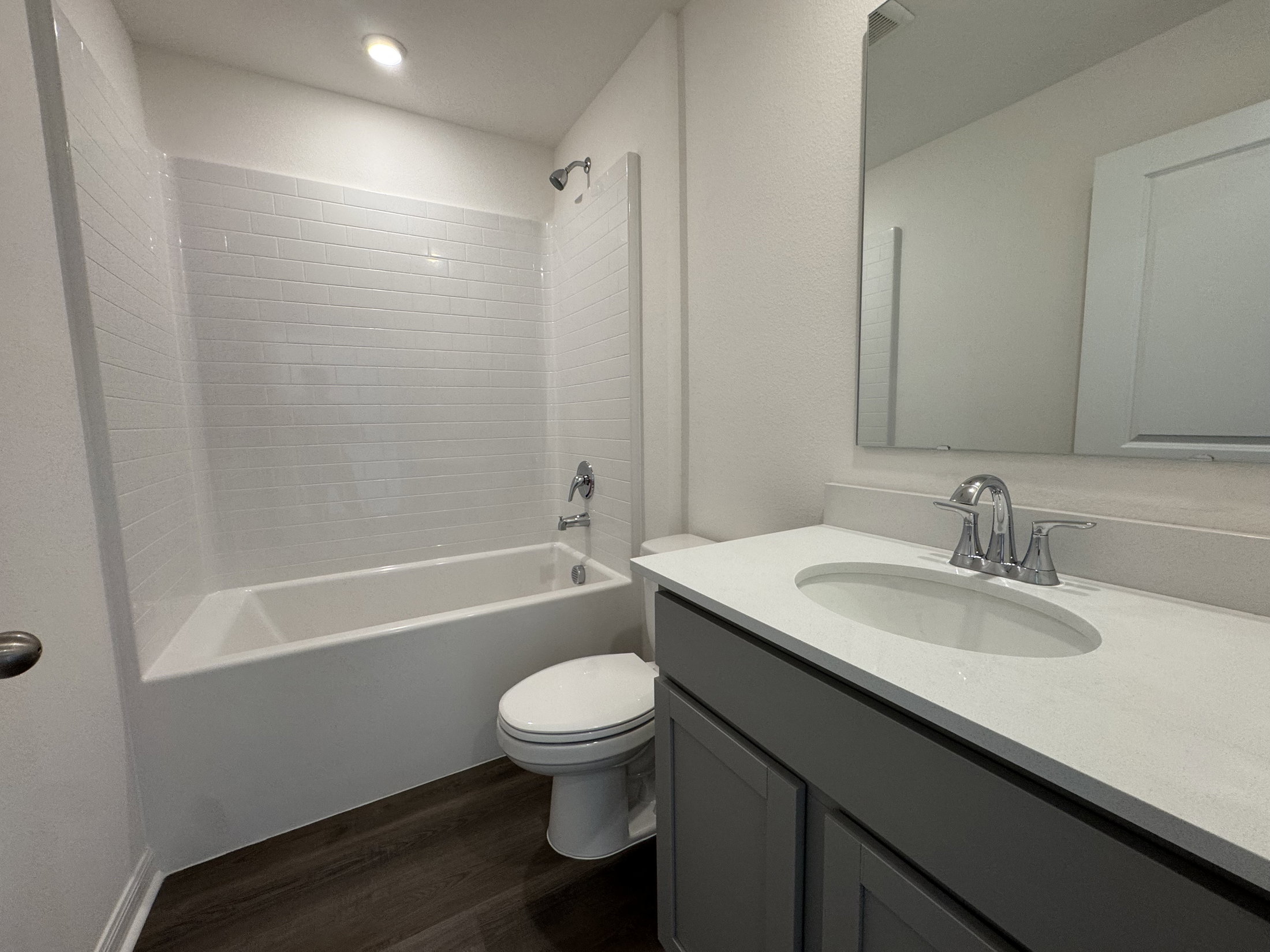 Modern bathroom featuring a bathtub with a shower, a white vanity with a circular sink, and light-colored walls.