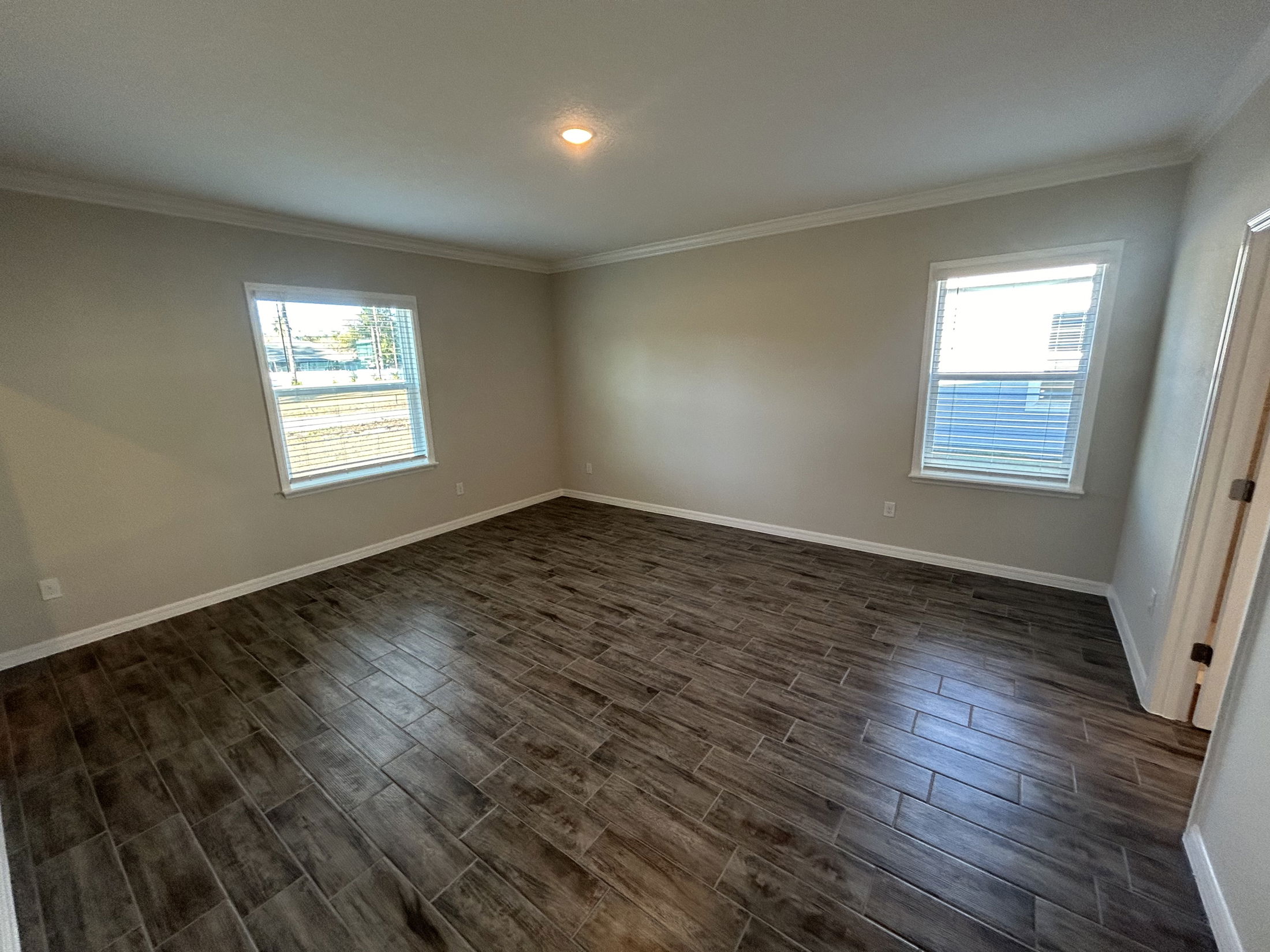 Spacious and bright empty room with large windows and modern tile flooring.