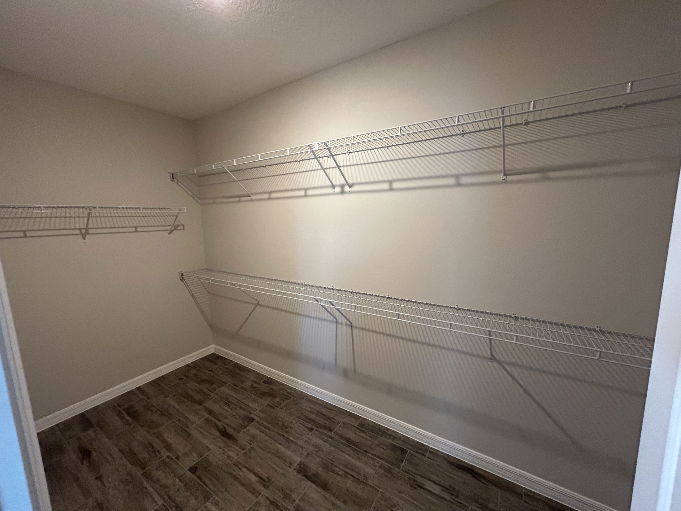 Empty closet with wire shelving and a tiled floor, providing ample storage space.