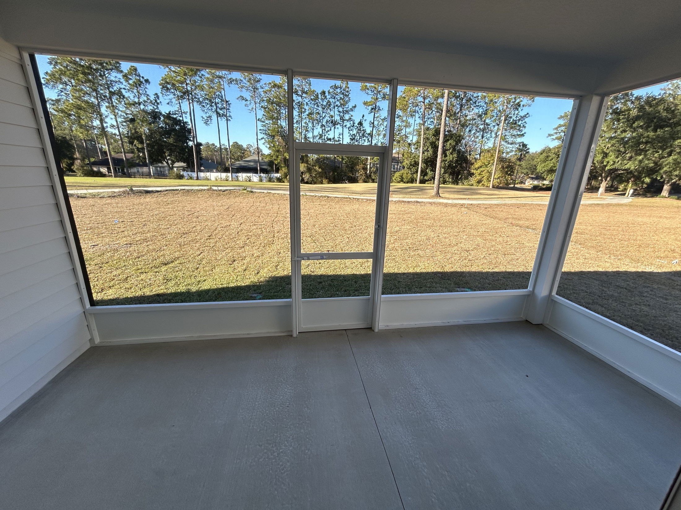 Interior view of a sunroom with large windows overlooking a grassy area and trees.