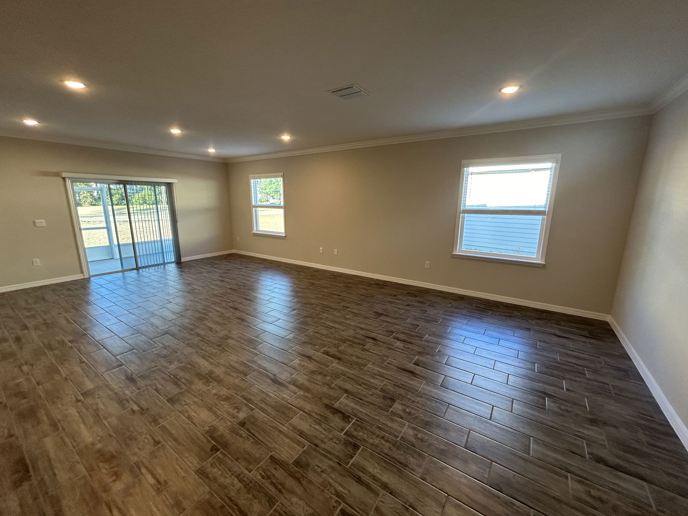 Spacious living room with beautiful wooden tile flooring and large windows for natural light.