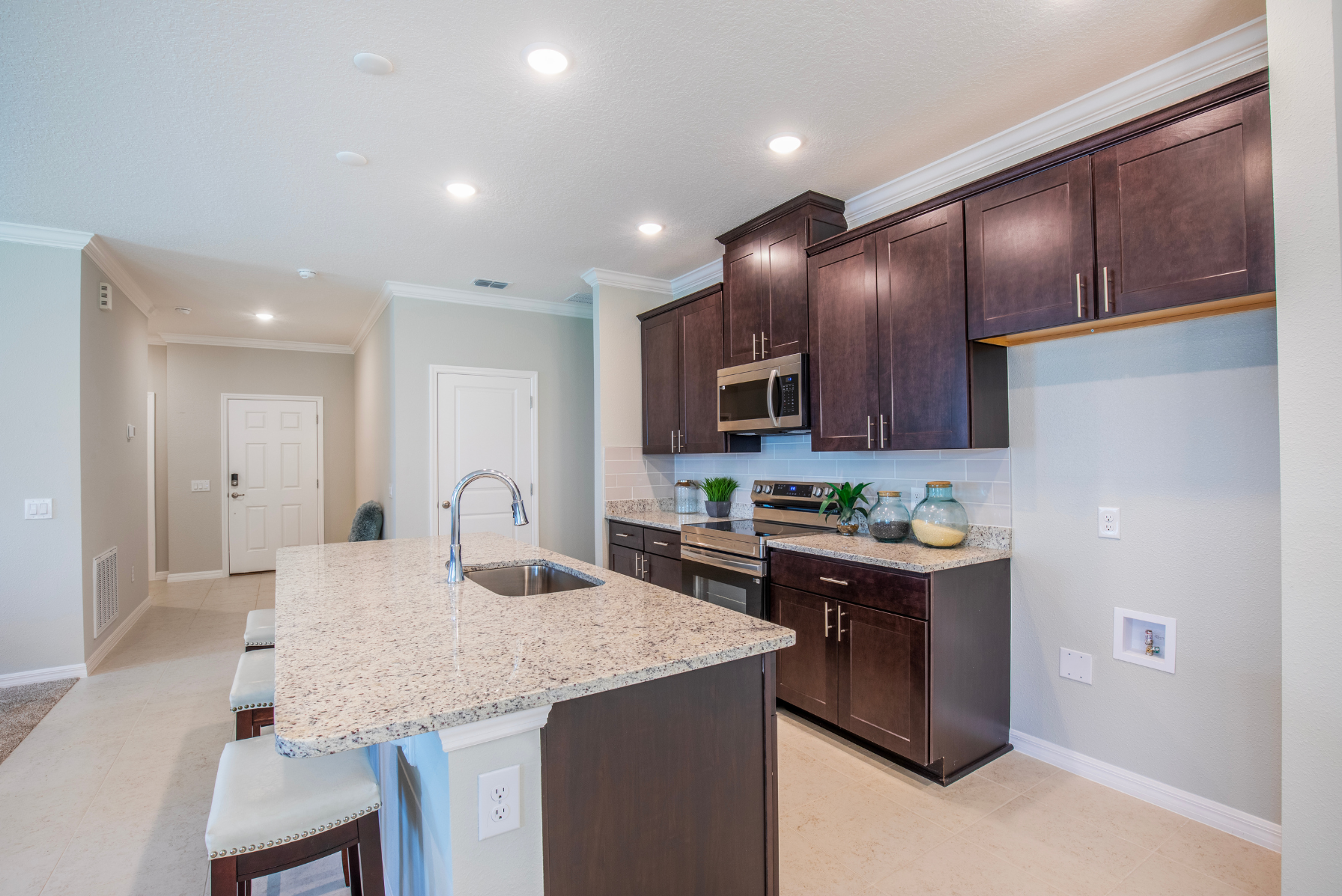 Modern kitchen with granite countertops, dark wood cabinets, stainless steel appliances, and recessed lighting.