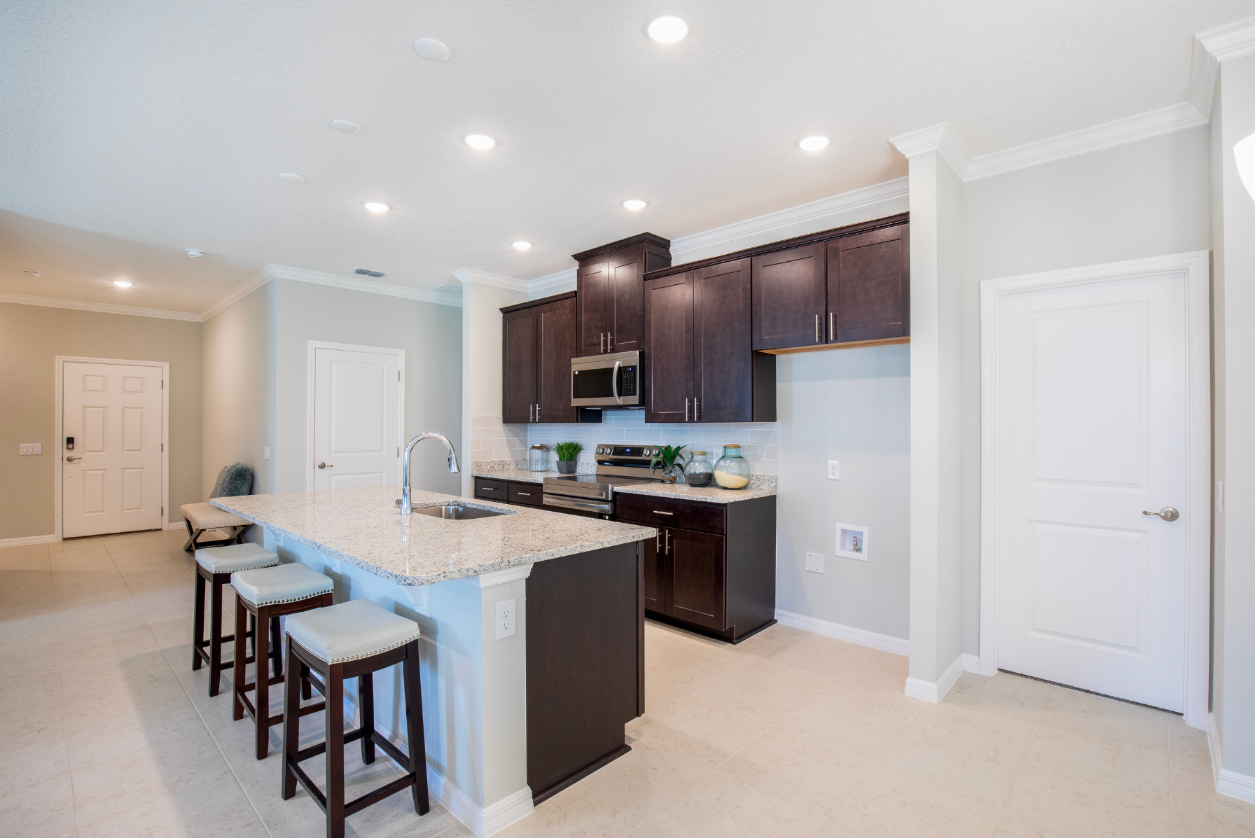 Modern kitchen with dark wood cabinets, granite countertops, and bar seating in a bright, open-concept design.