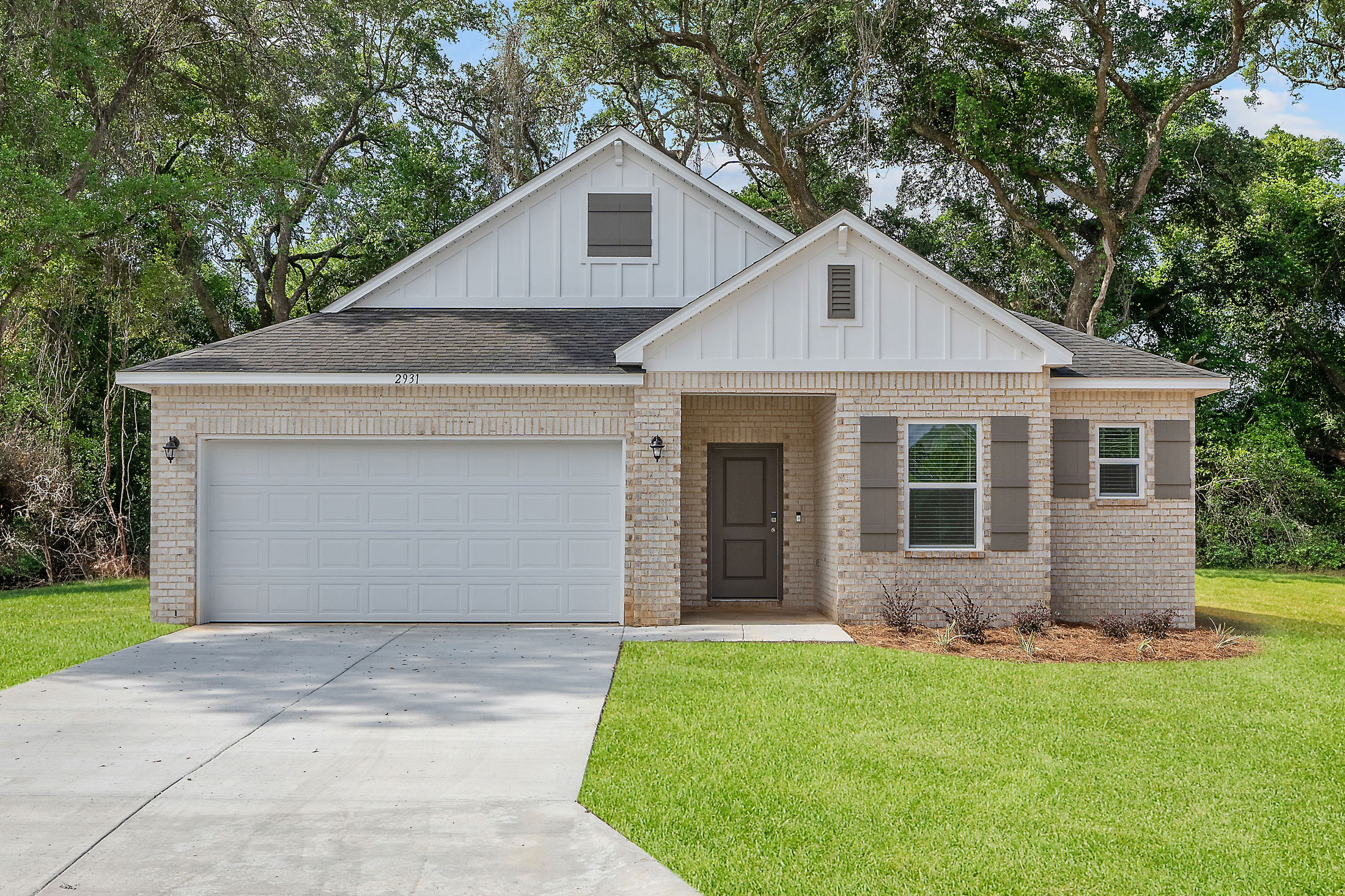 Modern single-story brick house with two-car garage and well-kept front lawn.