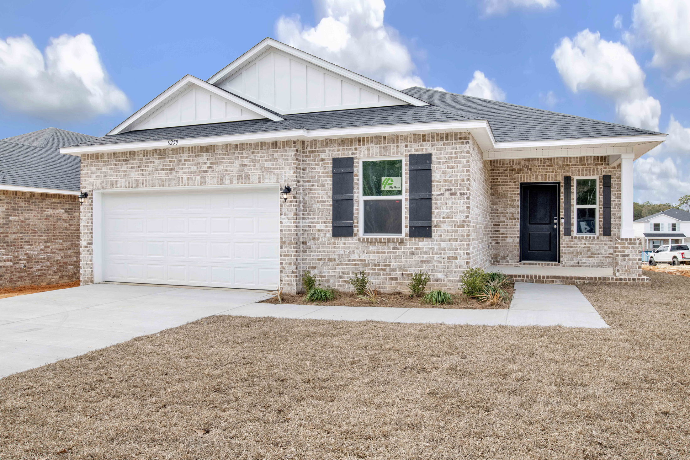 Modern single-story brick house with a two-car garage and manicured lawn.